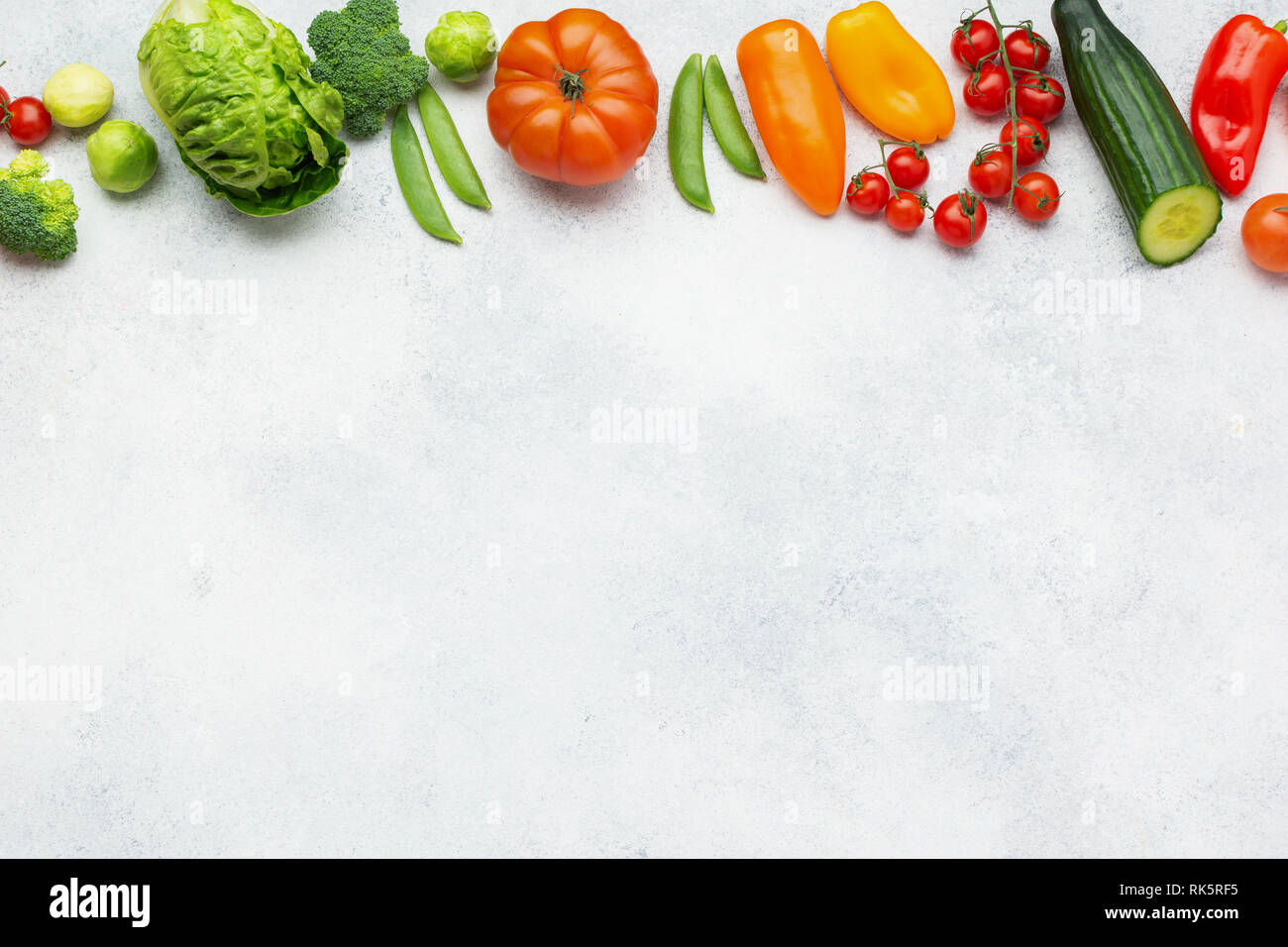 Ortaggi freschi di sfondo, Pomodori Cetrioli lattuga pepe cipollina broccoli piselli sul tavolo bianco, vista dall'alto, copia di spazio, il fuoco selettivo Foto Stock
