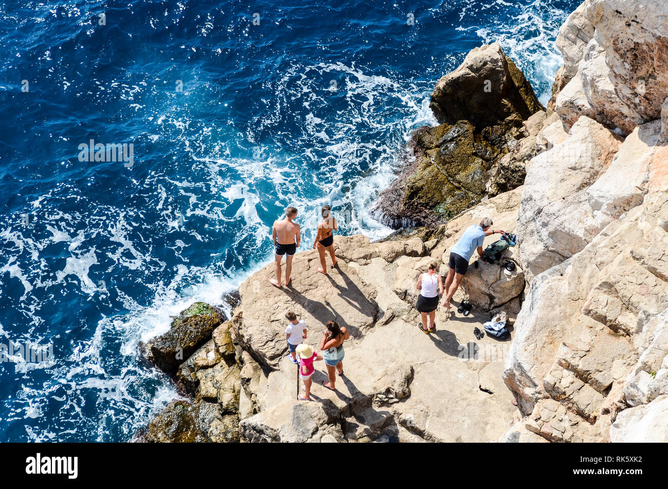 Visitatori di Dubrovnik sulle rocce del mare Adriatico Foto Stock