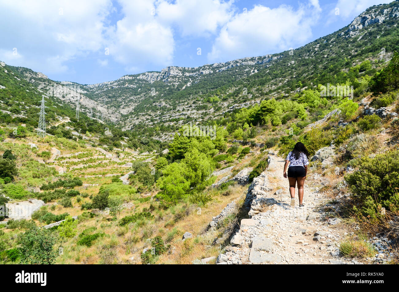 Donna africana che cammina sul sentiero escursionistico Vidova Gora sull'isola di Brac, Croazia Foto Stock