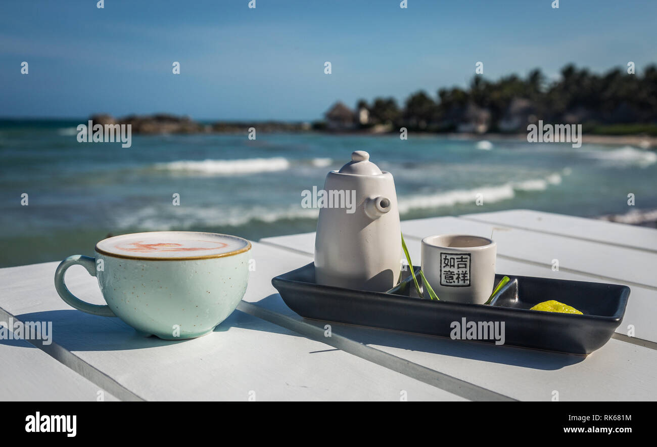 Cocktail serviti su un giapponese di set per il tè e il blu chiaro cup con l'oceano sullo sfondo bianco e i toni di blu Foto Stock