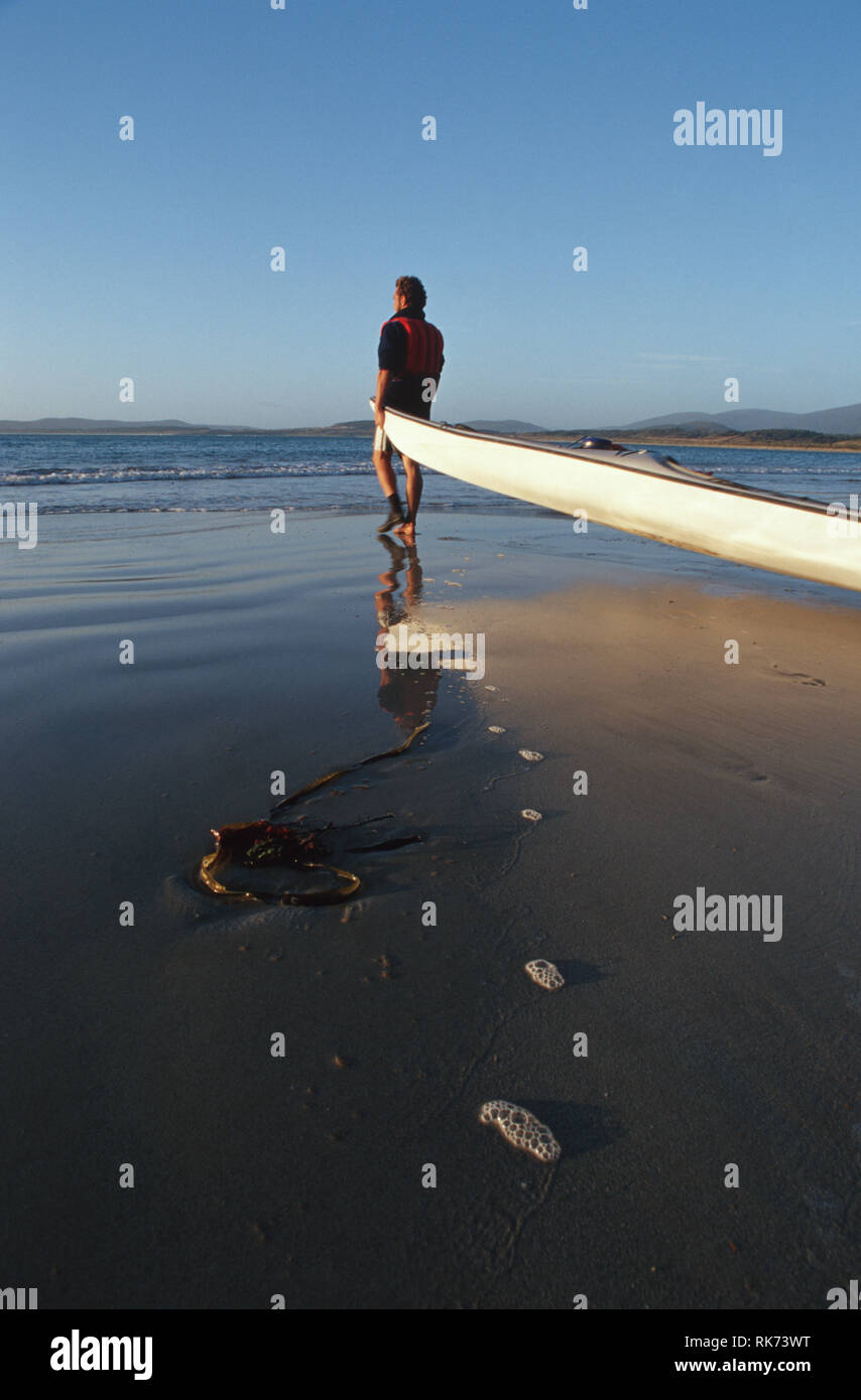 Didascalia: Bruny Island, Tasmania, Australia - Gen 2003. Un uomo prendendo il suo kayak di mare fino all'oceano off Bruny Island in Sud Tasmania. Lunga e s Foto Stock