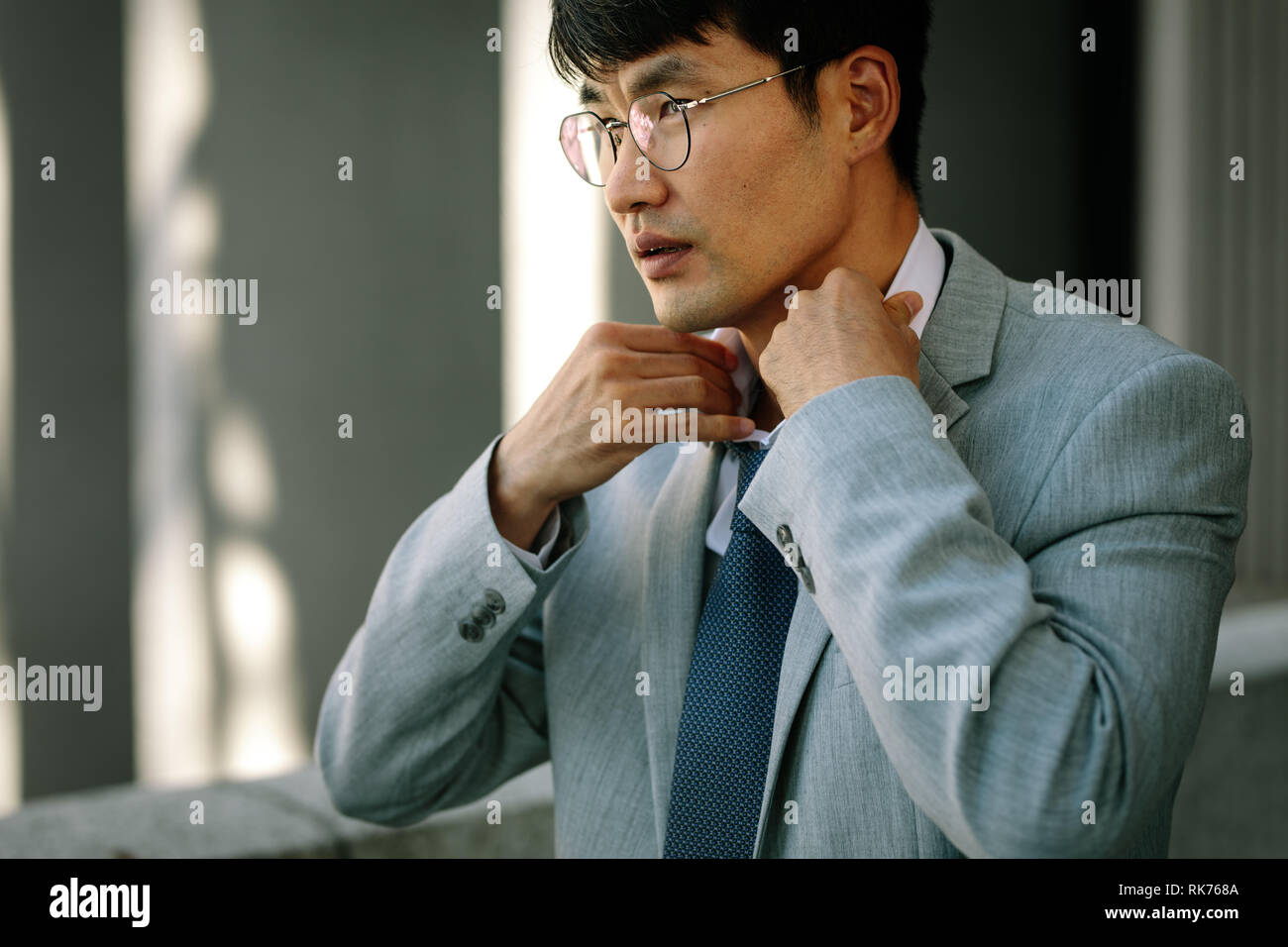uomo d'affari che si adatta alla cravatta. Asiatico business professionale in tuta regolando la sua cravatta. Foto Stock
