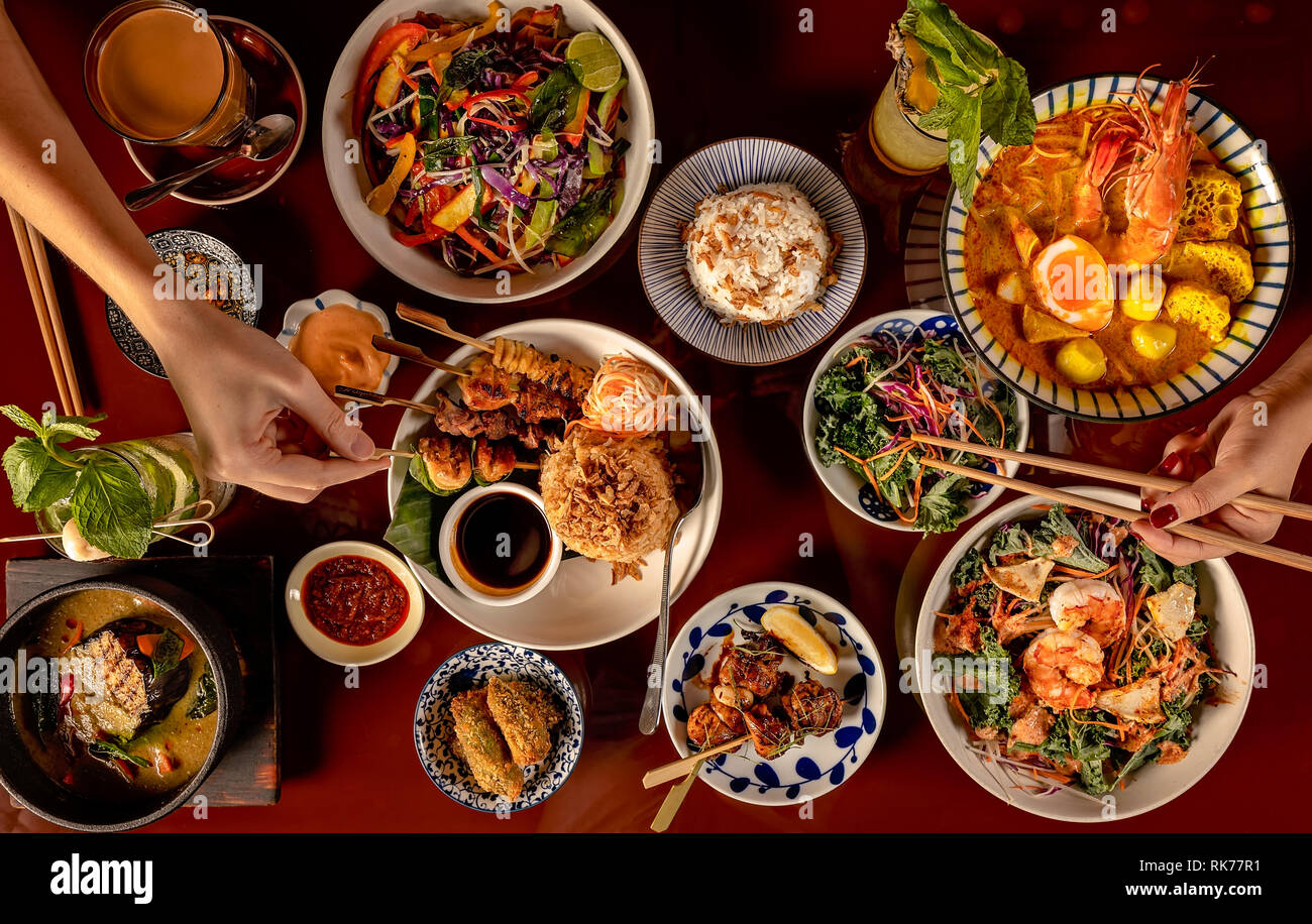 Selezione di piatti thailandesi, vista dall'alto verso il basso con diversi piatti come zuppe, spiedini, insalate, bevande e dessert. Foto Stock