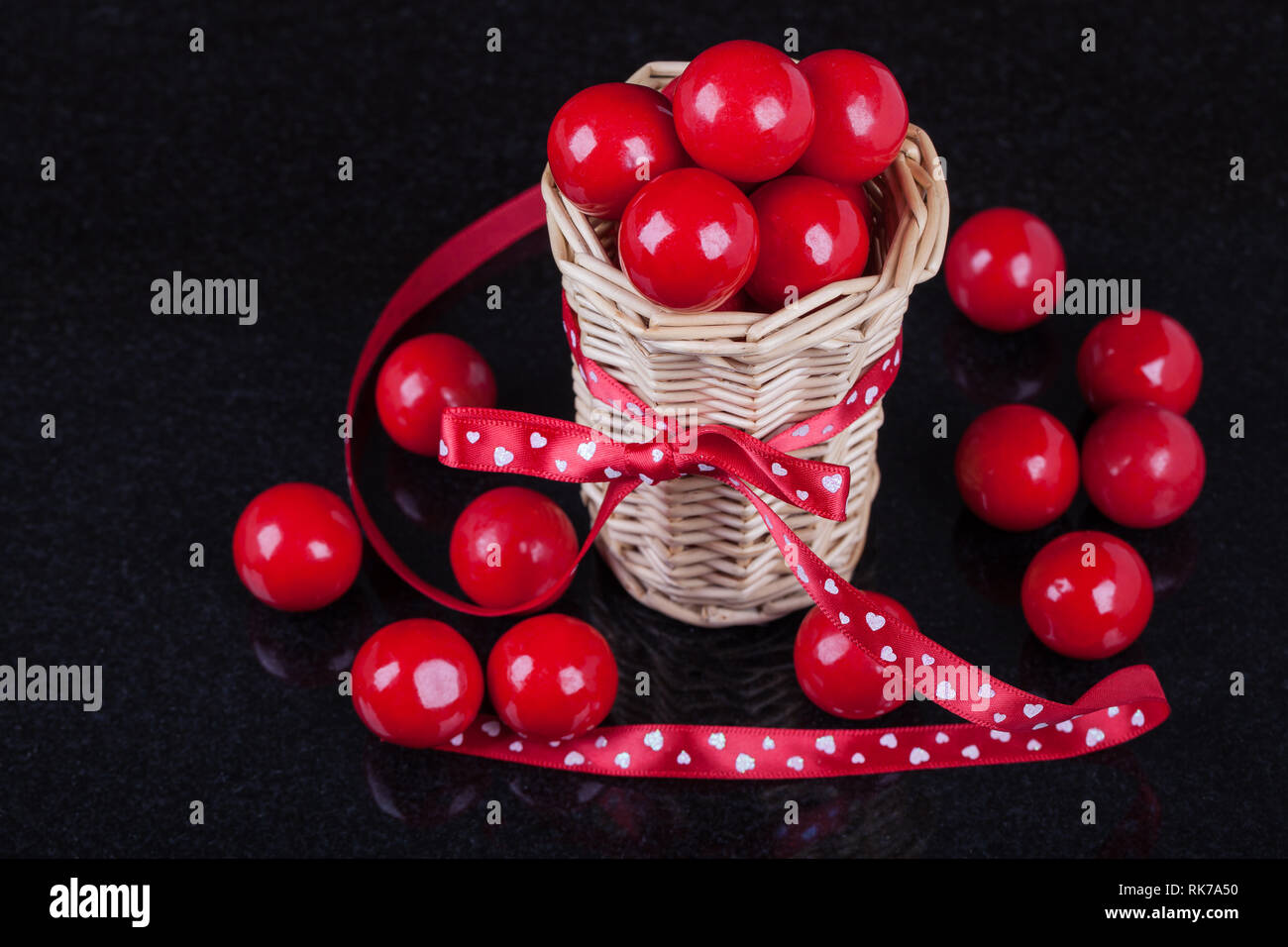 Il giorno di San Valentino concetto foto orizzontale, basket e dolci rossi su sfondo nero Foto Stock