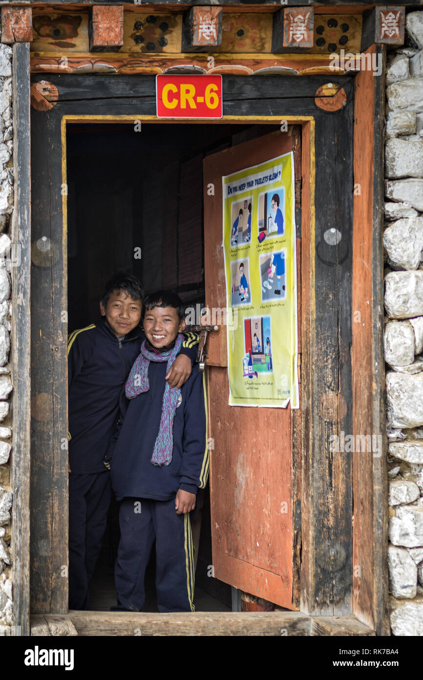 Due ragazzi felice presso la porta di una classe a Laya scuola, Gasa distretto, Snowman Trek, Bhutan Foto Stock