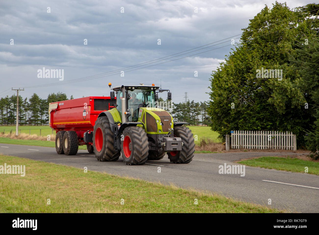 Un trattore che traina un seme bin rimorchio scarica il seme da la trincia semovente in Canterbury, Nuova Zelanda Foto Stock