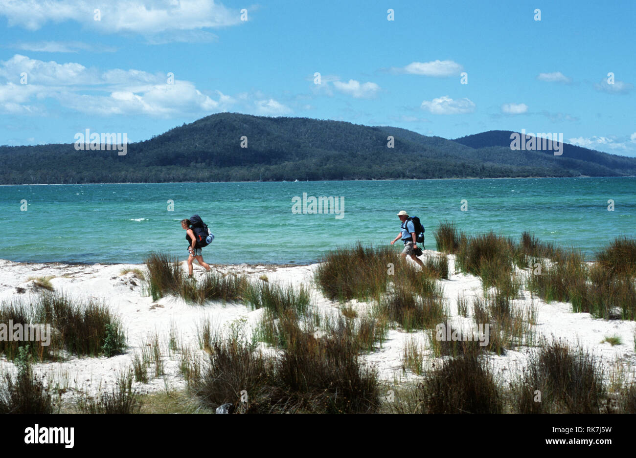 Gli ospiti di Maria Island a piedi attraversano uno dei la maggior parte delle spiagge del sud di Maria Island per la loro notte di camp. La tendenza più recente sul trattore della Tasmania Foto Stock