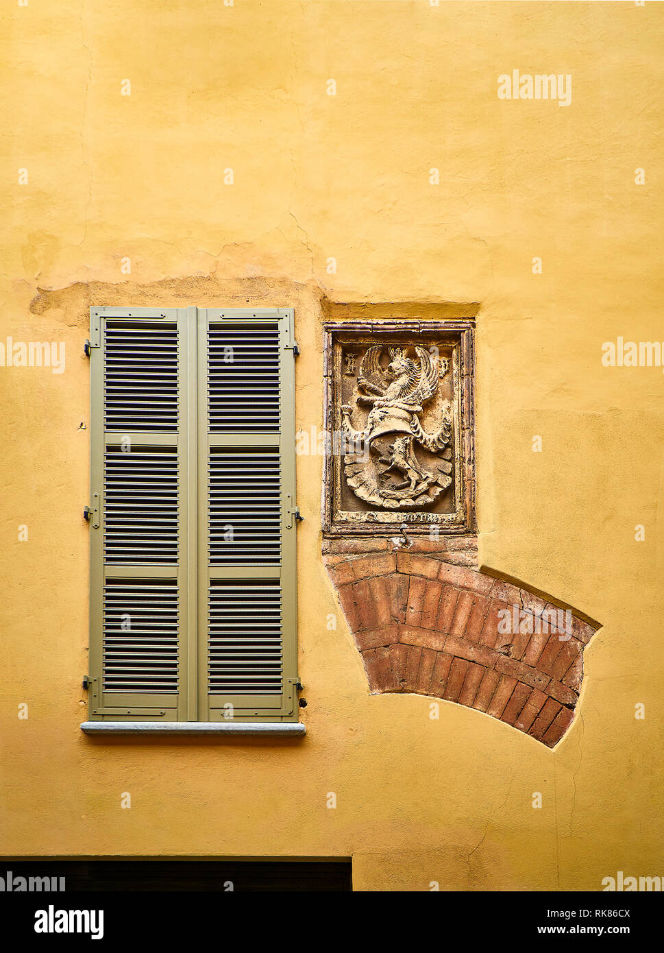 Vestigia di un arco medievale e un blasone su una facciata. Asti, Piemonte, Italia. Foto Stock