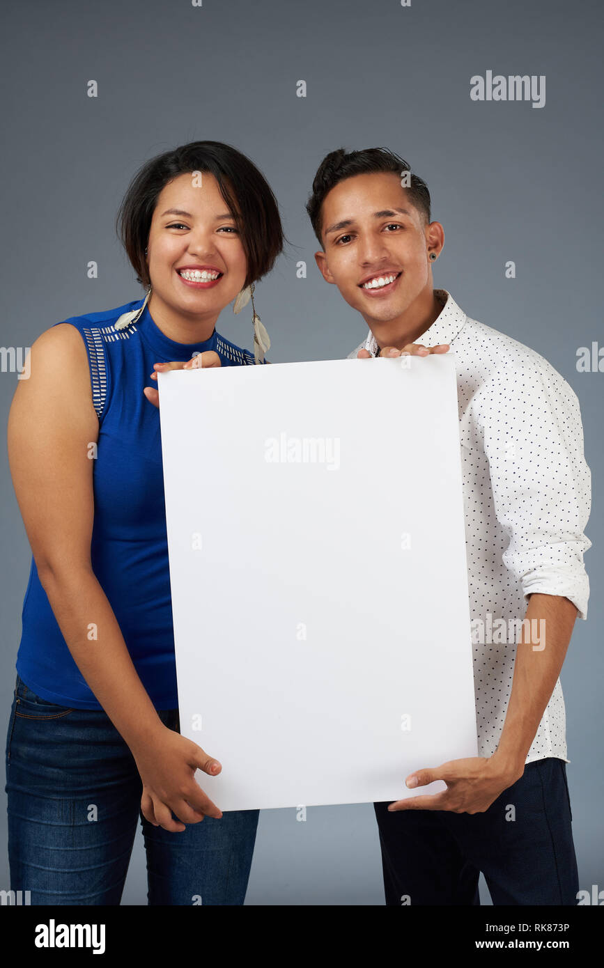 Sorridente giovane tenere banner bianco isolato su sfondo per studio Foto Stock