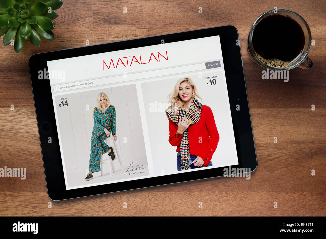 Il sito web di Matalan è visto su un tablet iPad, su di un tavolo di legno lungo con un caffè espresso e una pianta di casa (solo uso editoriale). Foto Stock
