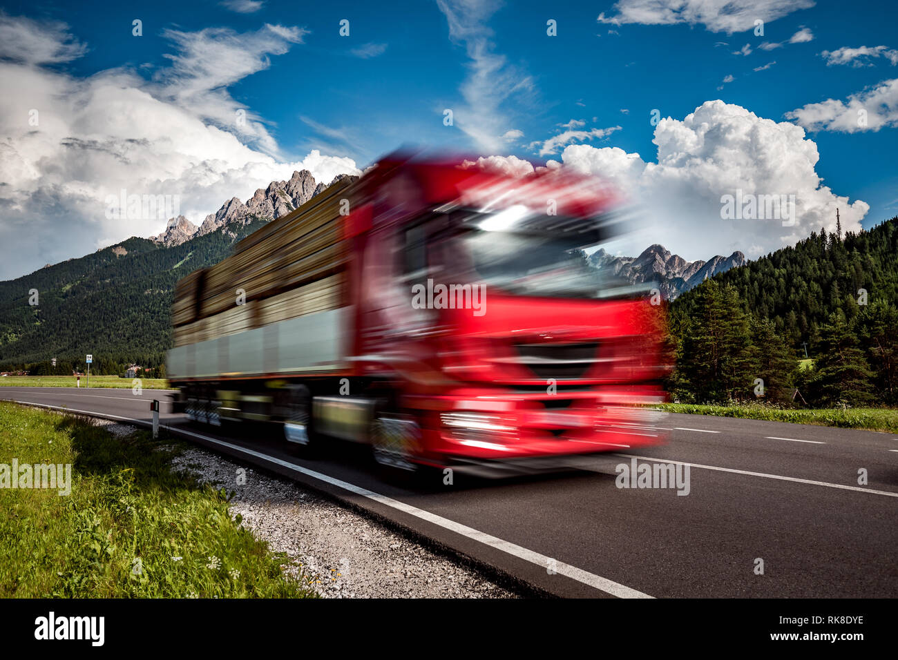 Legname camion precipita l'autostrada sullo sfondo delle Alpi. Carrello Car in motion blur. Foto Stock