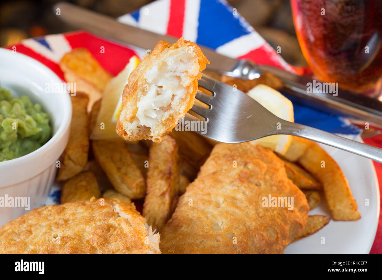 Una piastra di Inglese tradizionale con pesce e patatine con fiacco piselli. Foto Stock