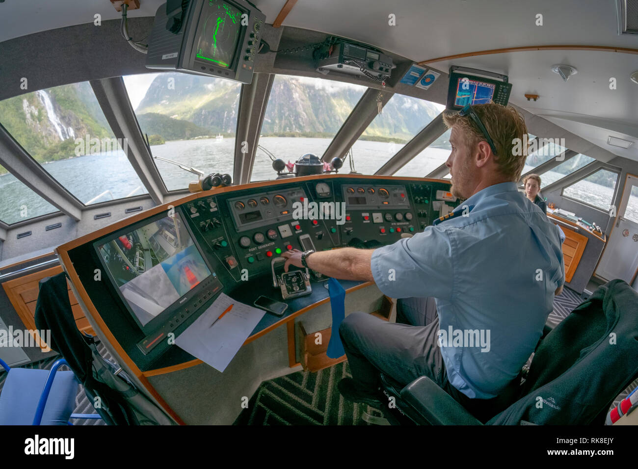 Immagine fisheye del ponte di Milford sovrano una barca per gite nel Parco Nazionale di Fiordland, Milford Sound. Isola del Sud della Nuova Zelanda Foto Stock