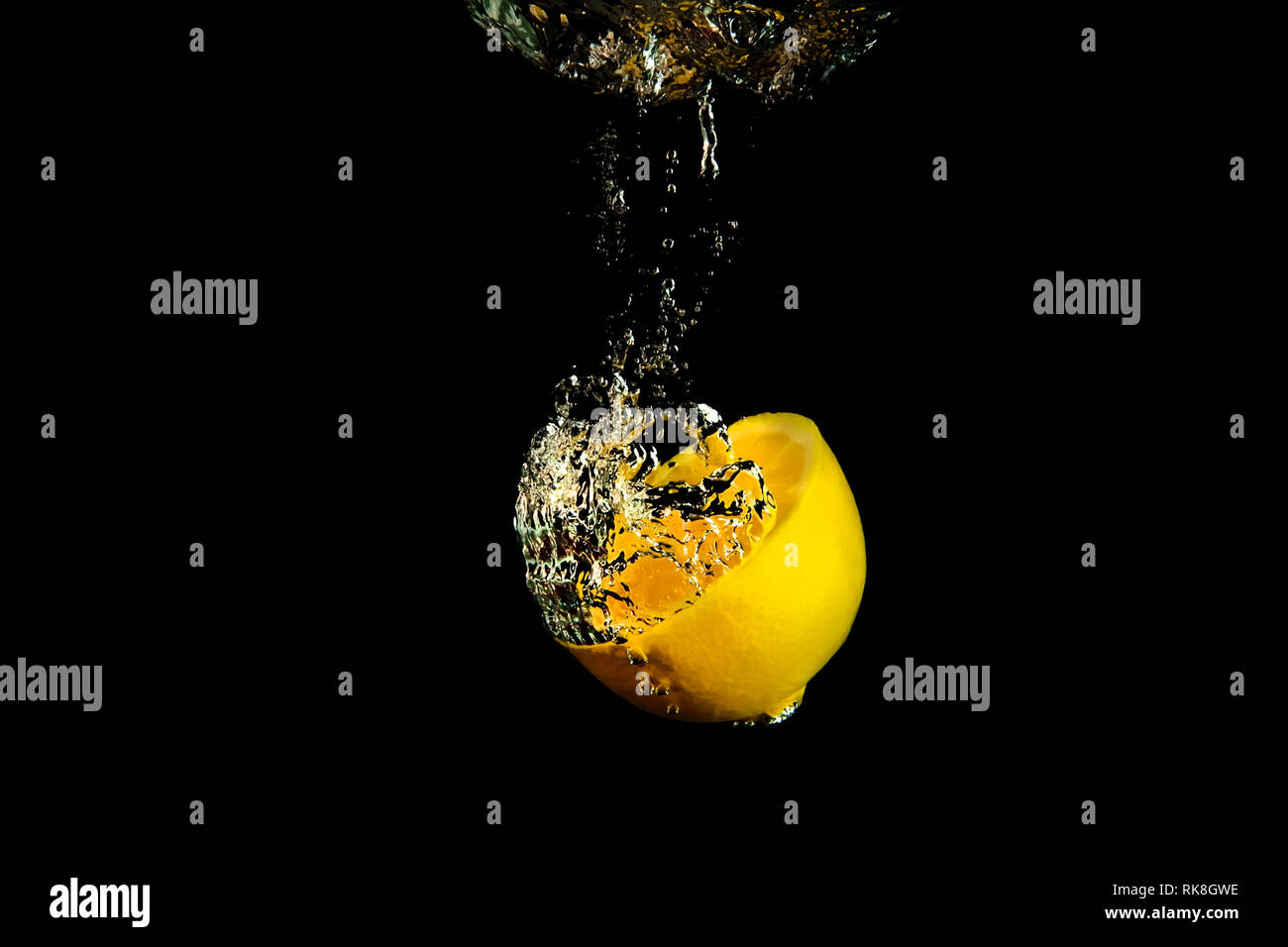Mezzo limone caduta in acqua su sfondo nero Foto Stock