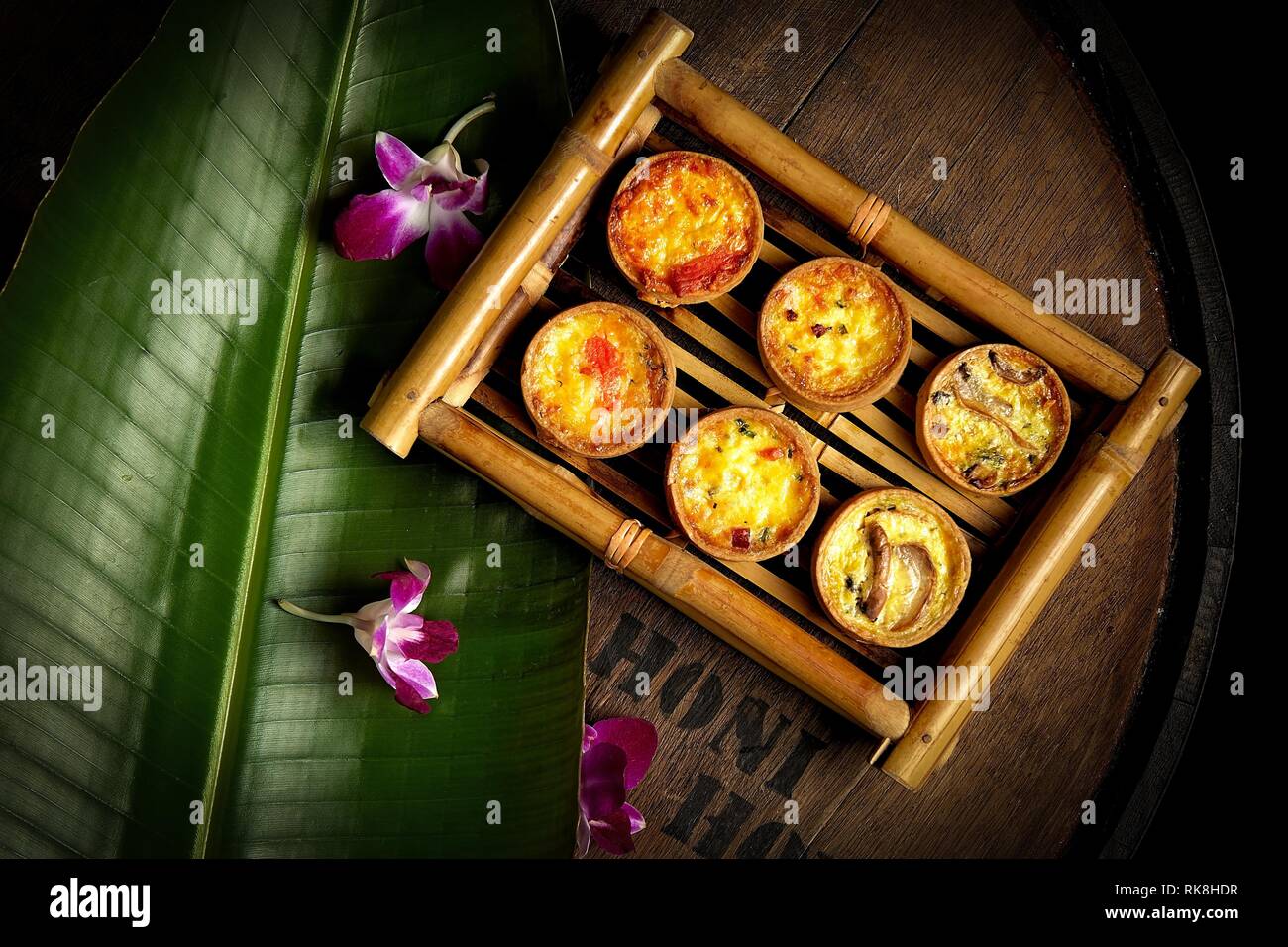 Foto piatta di sei mini quiches servito come un snack bar su un vassoio di bambù Foto Stock