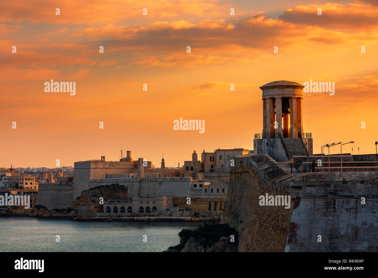 Vista di assedio Bell Memoriale di guerra come vecchie mura e fortezza sullo sfondo sotto il bellissimo cielo serale a La Valletta, Malta. Foto Stock