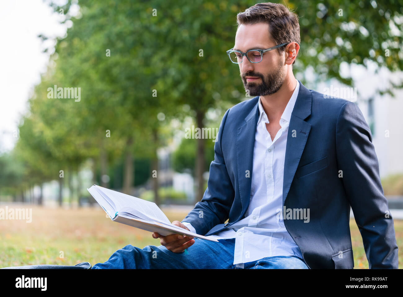 Imprenditore serio libro di lettura nel parco Foto Stock