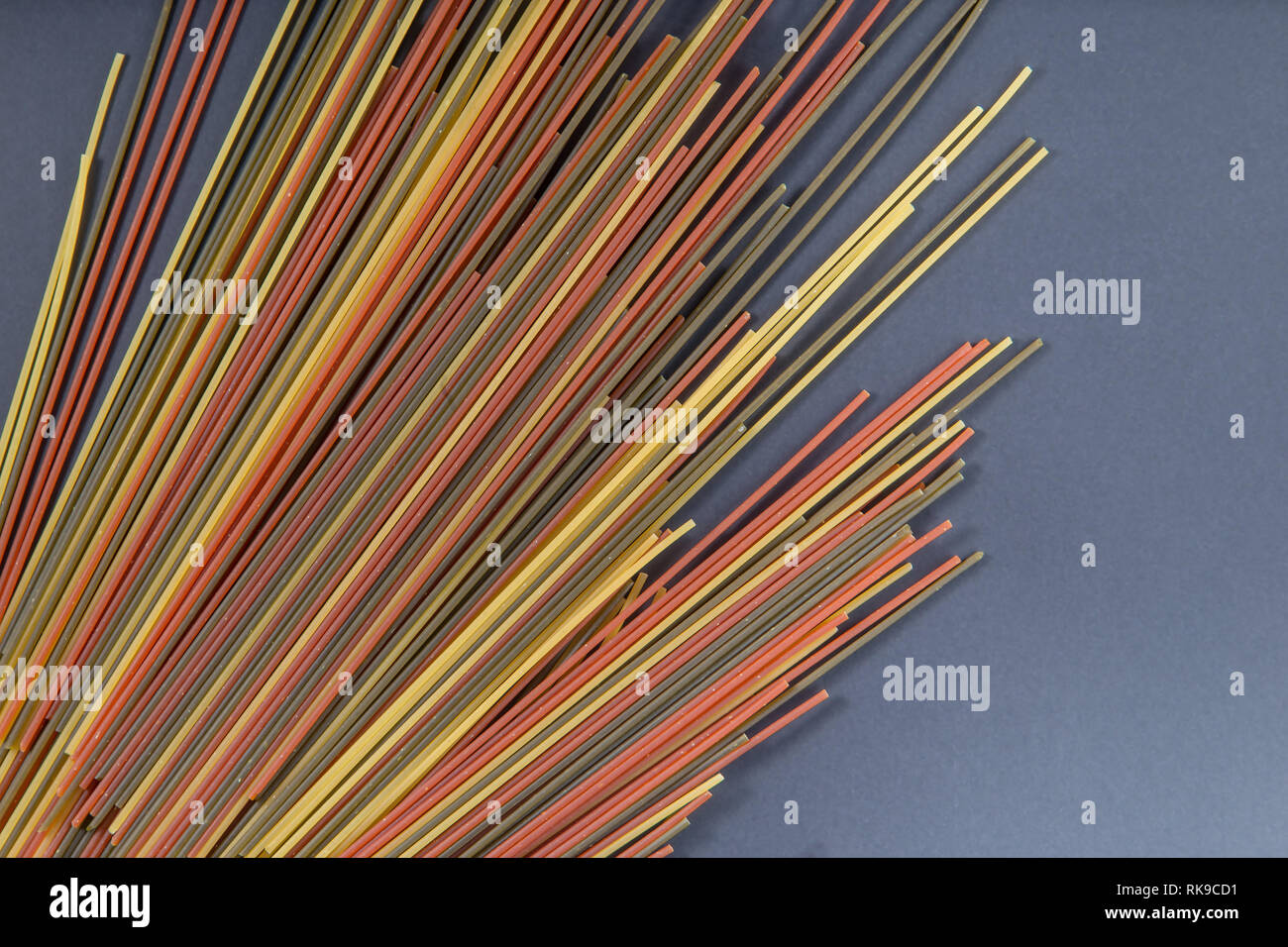 Italiano colorato grezzo intero spaghetti di grano su sfondo nero Foto Stock