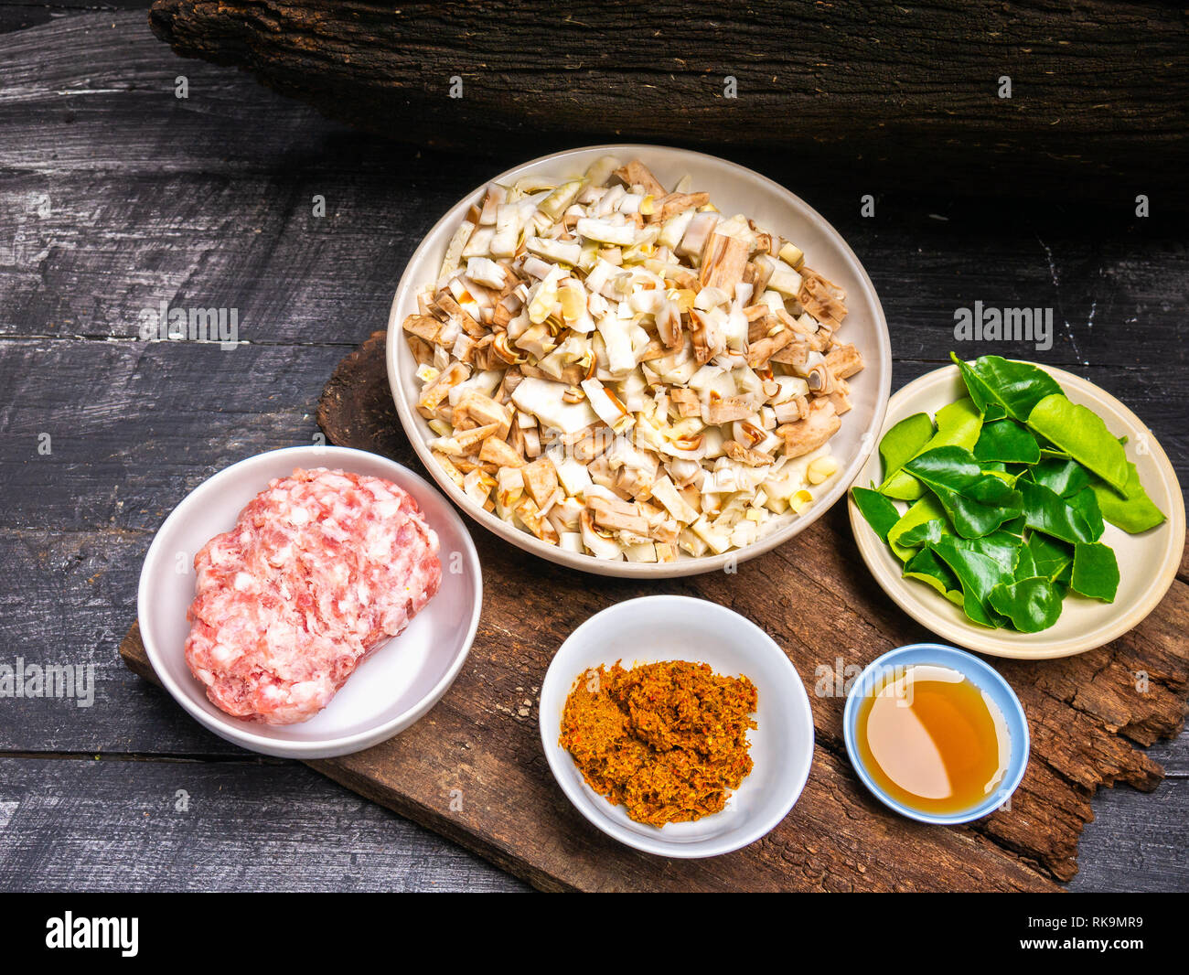 Ingredienti per la cottura di fritto di carne di maiale al curry e fette di bollito jackfruit giovani con foglie di bergamotto, salsa di pesce sul vecchio asse di legno dello sfondo. Foto Stock