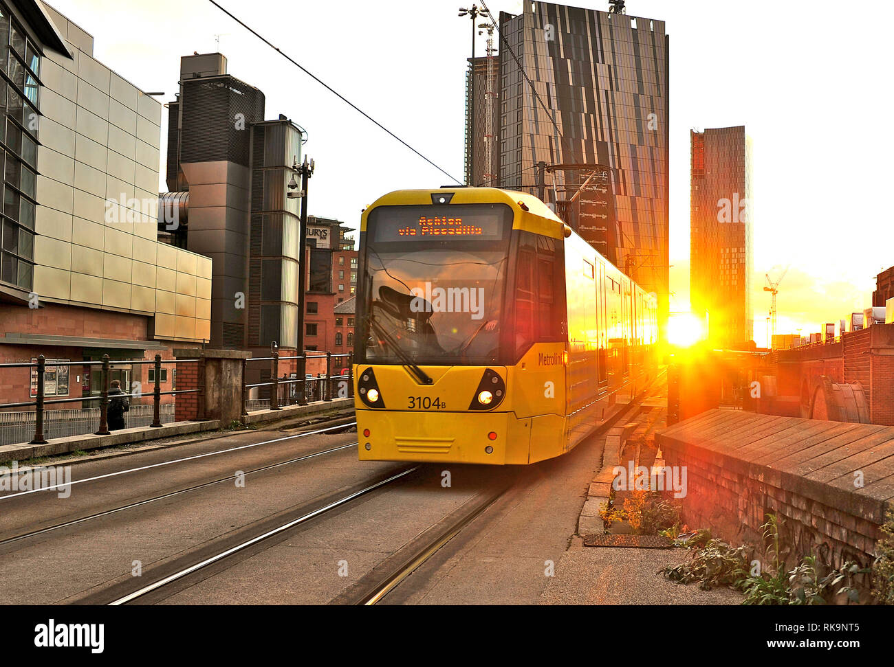 Tram della metropolitana di Manchester davanti al tramonto tra due isolati di appartamenti, Manchester, Inghilterra, Regno Unito Foto Stock