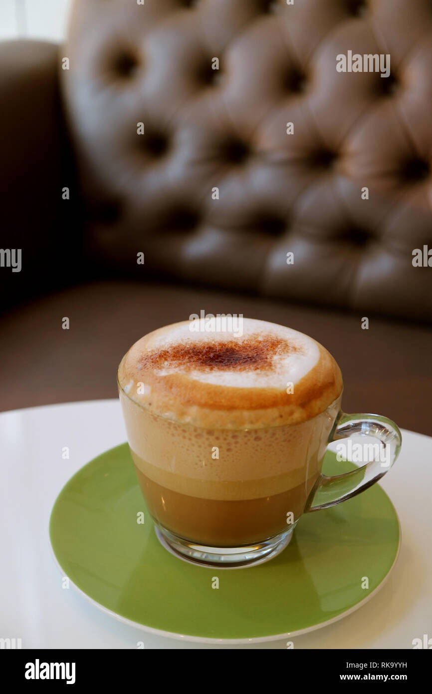 Tazza di soffice schiuma di latte caldo per caffè cappuccino sul tavolo  bianco con divano sfocate in background Foto stock - Alamy