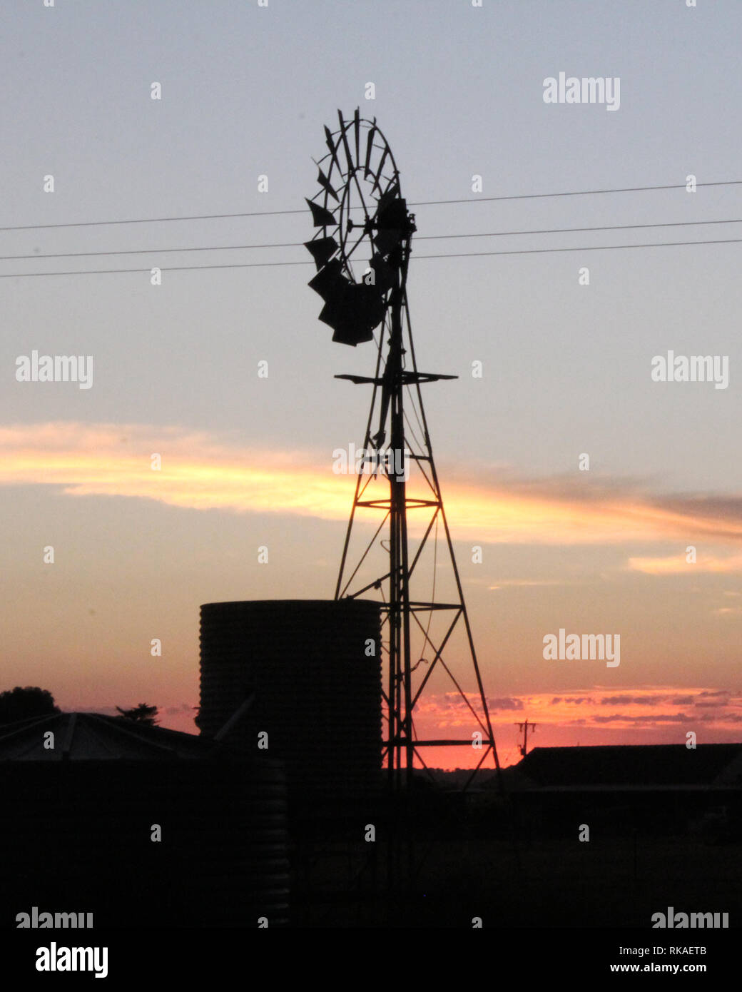 Un outback australiano mulino con il tramonto dietro di essa Foto Stock
