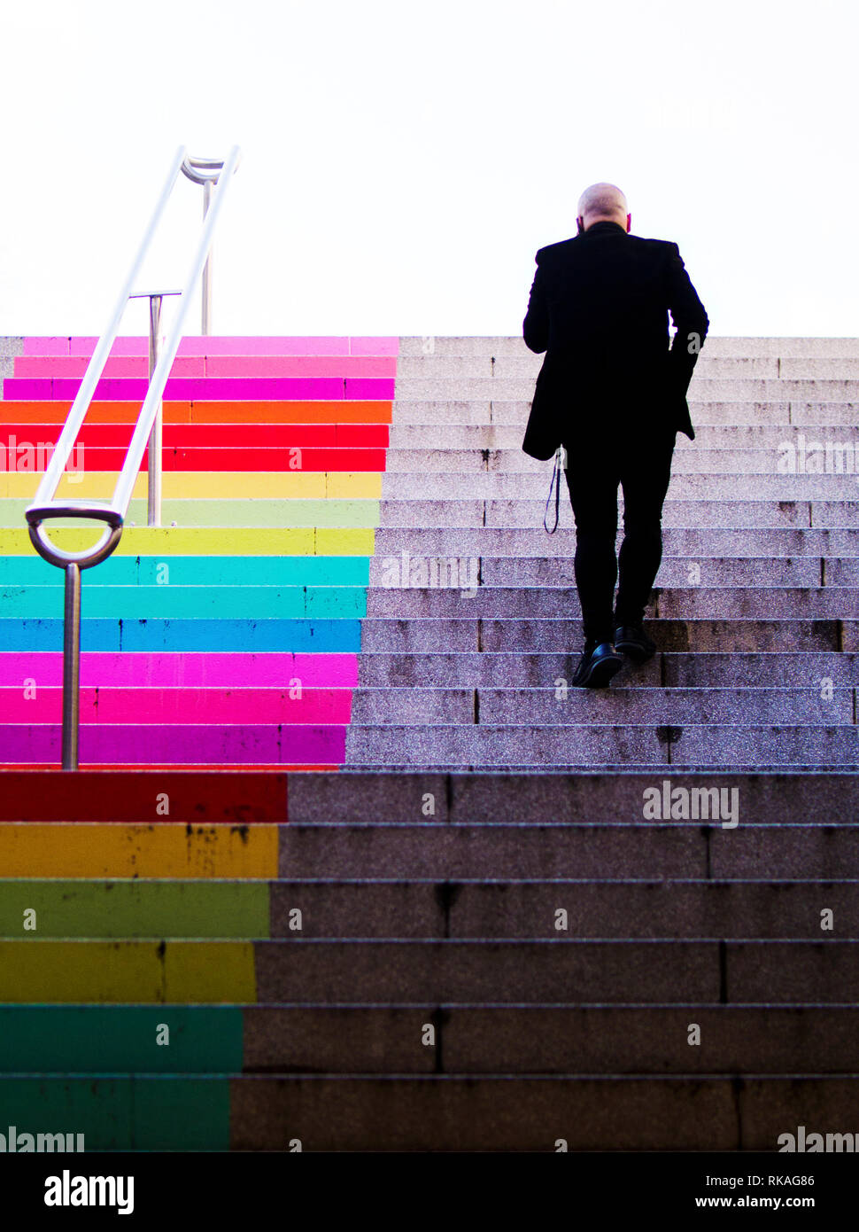 Imprenditore salendo le scale colorate Foto Stock