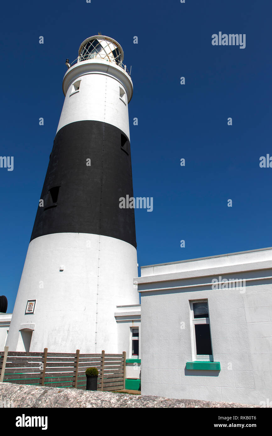 L'Alderney Mannez faro con cielo blu chiaro per spazio di copia Foto Stock