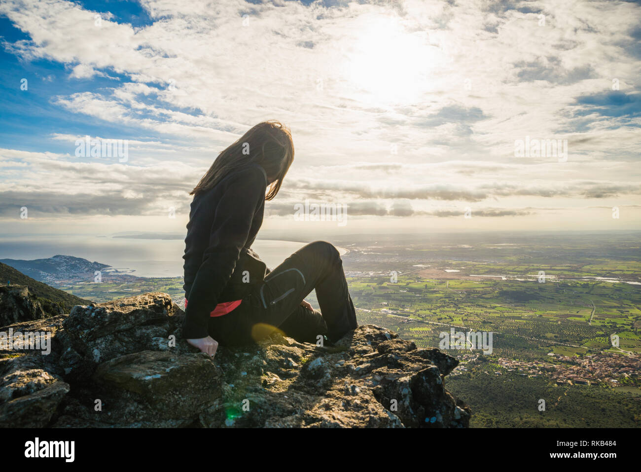 Ragazza seduta sul bordo di una scogliera ammirando lo splendido panorama, in mezzo alla natura, in Catalogna, Spagna Foto Stock
