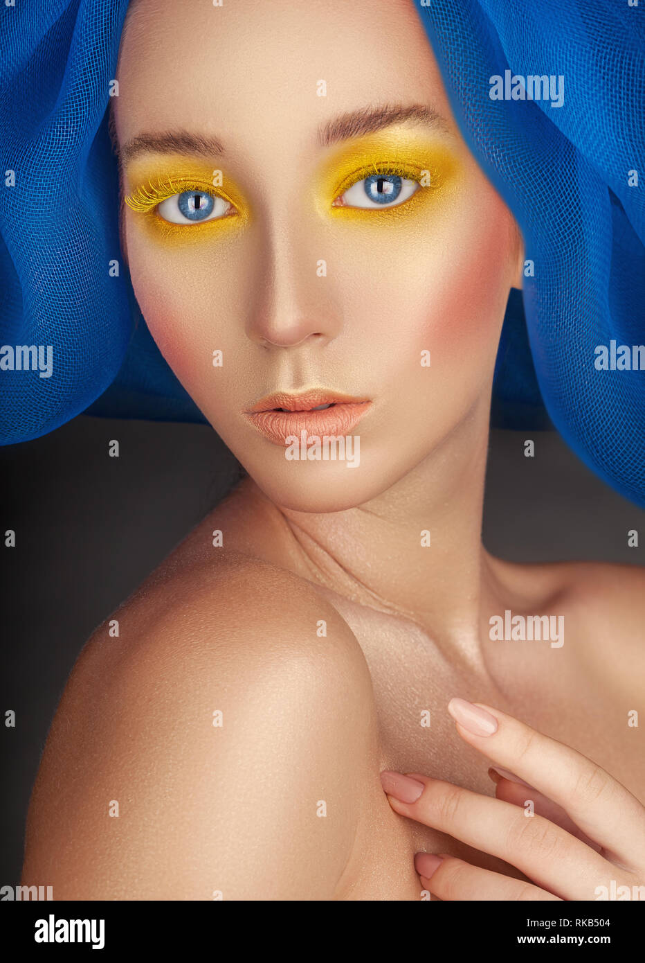 Ritratto di una donna bellissima con la moda per il make-up, luminoso giallo in polvere negli occhi e dŽcor blu sul suo capo Foto Stock