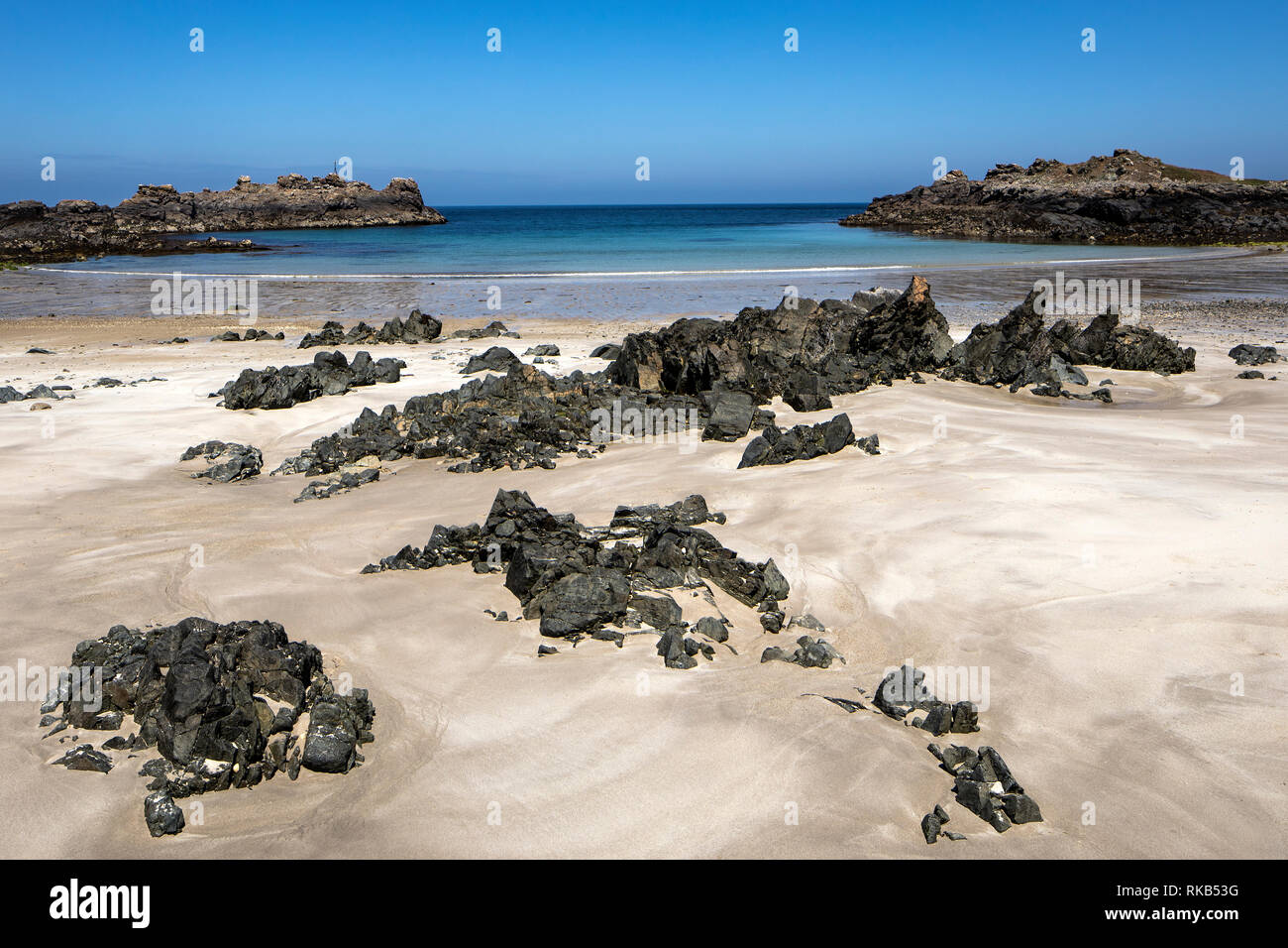 Il vecchio rocce nere e bianche sabbie di Saye Bay su Alderney. Foto Stock