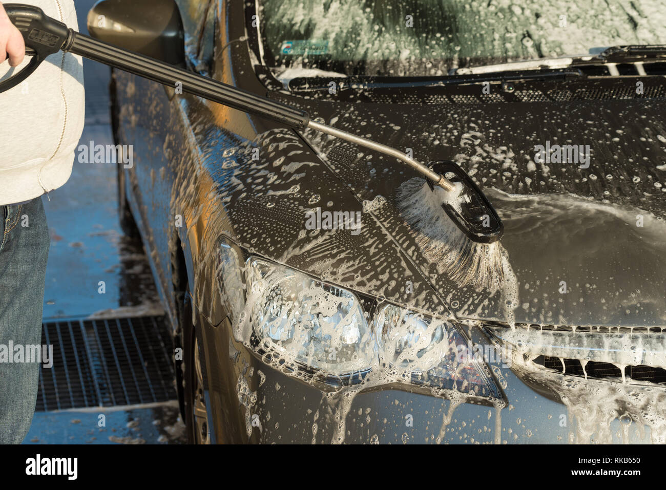 Il lavaggio delle auto utilizzando un pennello in un self-service lavaggio auto Foto Stock
