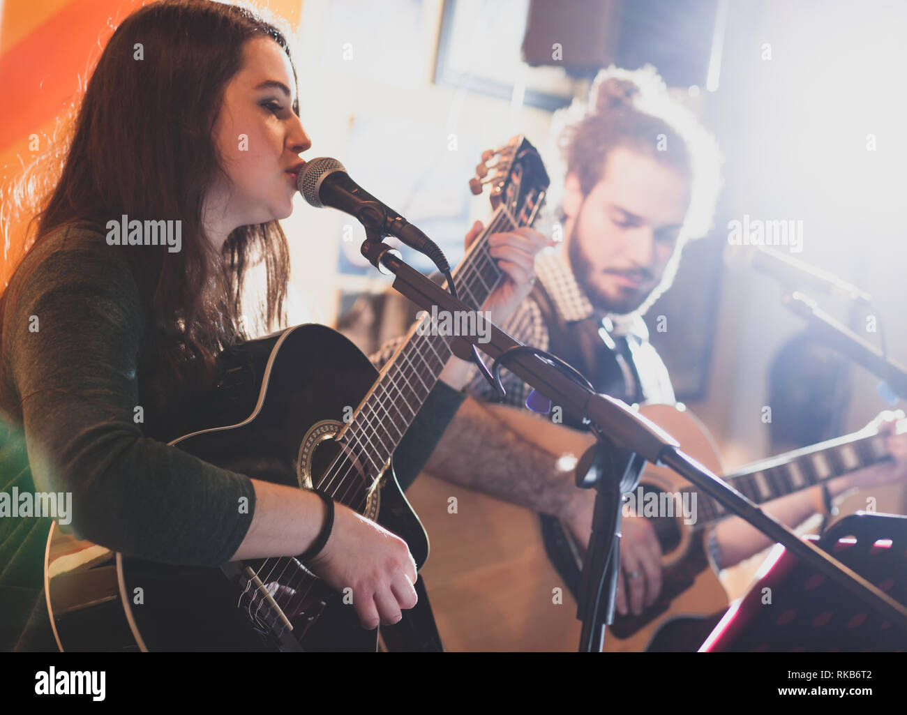Duetto di chitarristi che cantano durante una performance musicale. Retroilluminazione con bruciatore a fiamma viva. Foto Stock