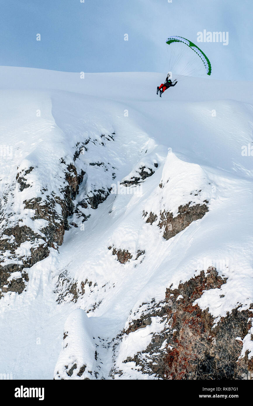 Velocità-battenti francesi nella località alpina di Courchevel. Un uomo vola con una velocità-flying wing su sci fuori da una scogliera sulla neve. Foto Stock