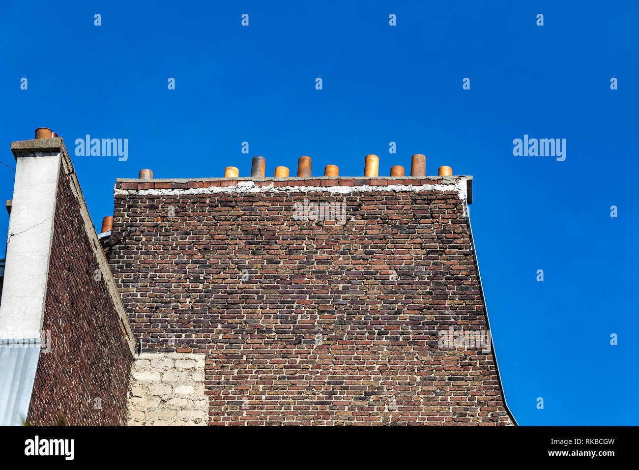 Elevato il vecchio muro di mattoni lato di un di un palazzo di appartamenti con camino di pile contro un profondo cielo blu , paris , France Foto Stock