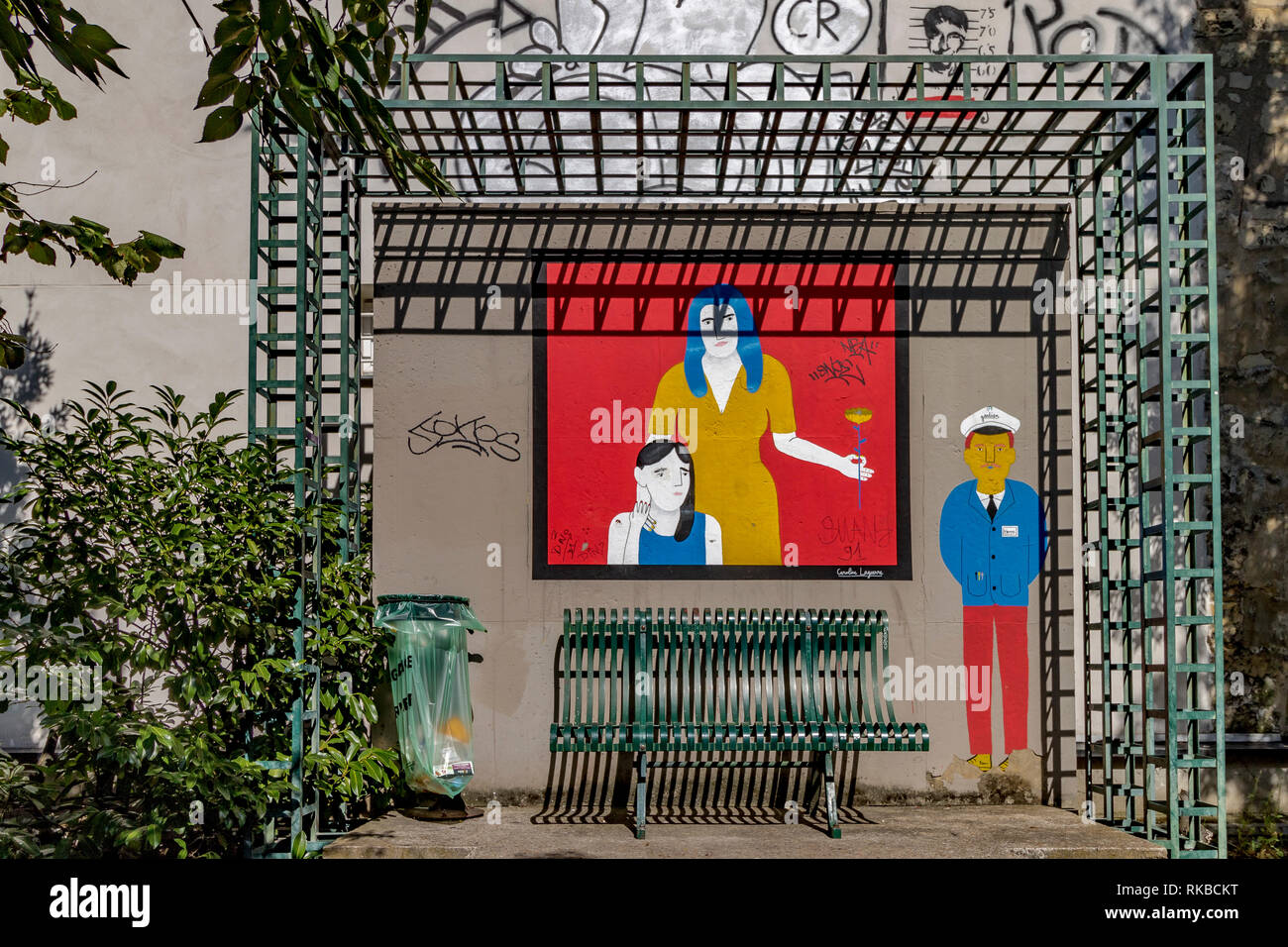 Un verde banco di metallo con artwork dipinta sulla parete lungo la Promenade Plantée un elevato giardino pubblico marciapiede , paris , France Foto Stock