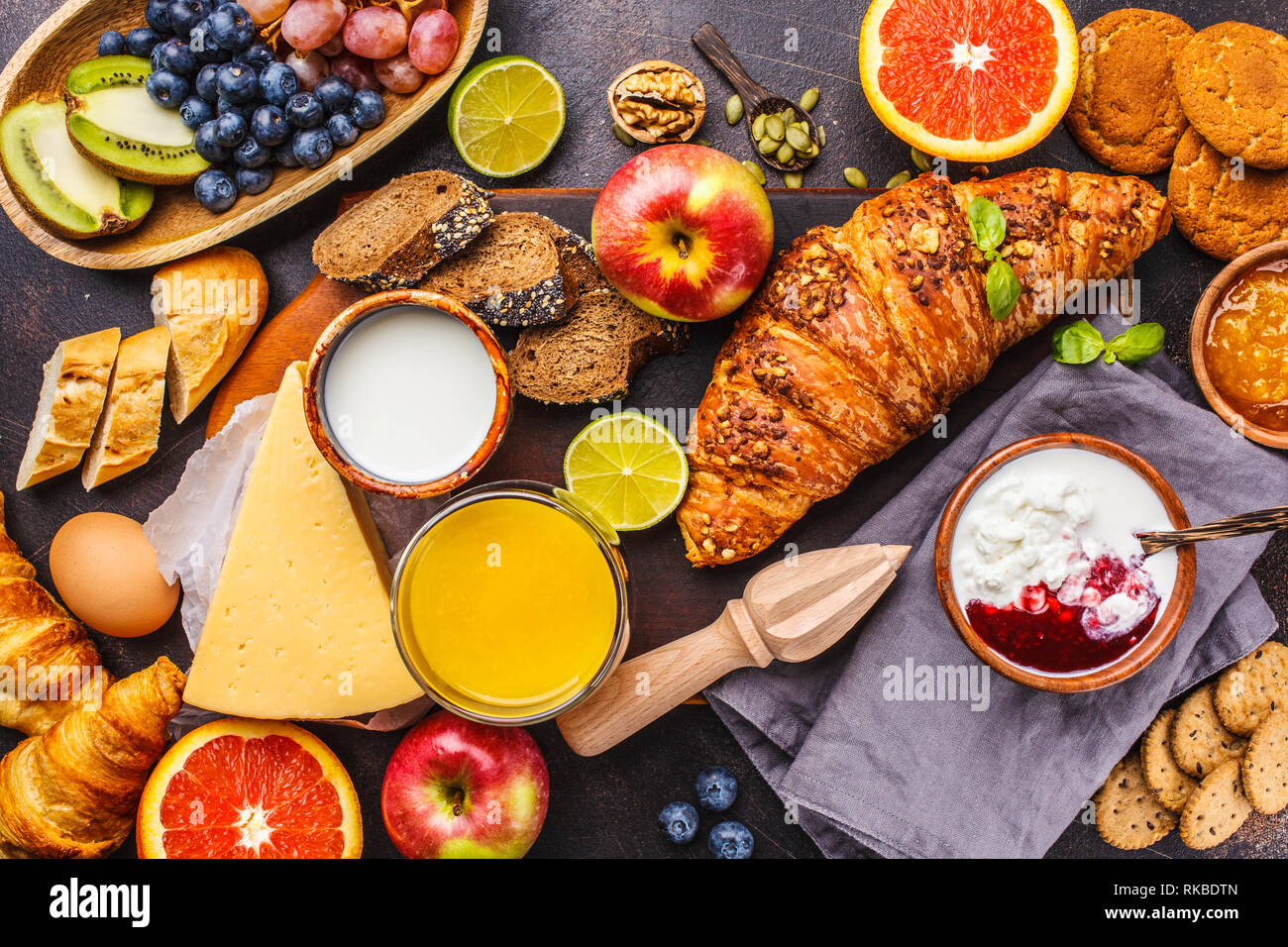 Una sana prima colazione bilanciata su uno sfondo scuro. Muesli, latte,  succo di frutta, croissant, formaggio, biscotti e frutta, vista dall'alto  Foto stock - Alamy