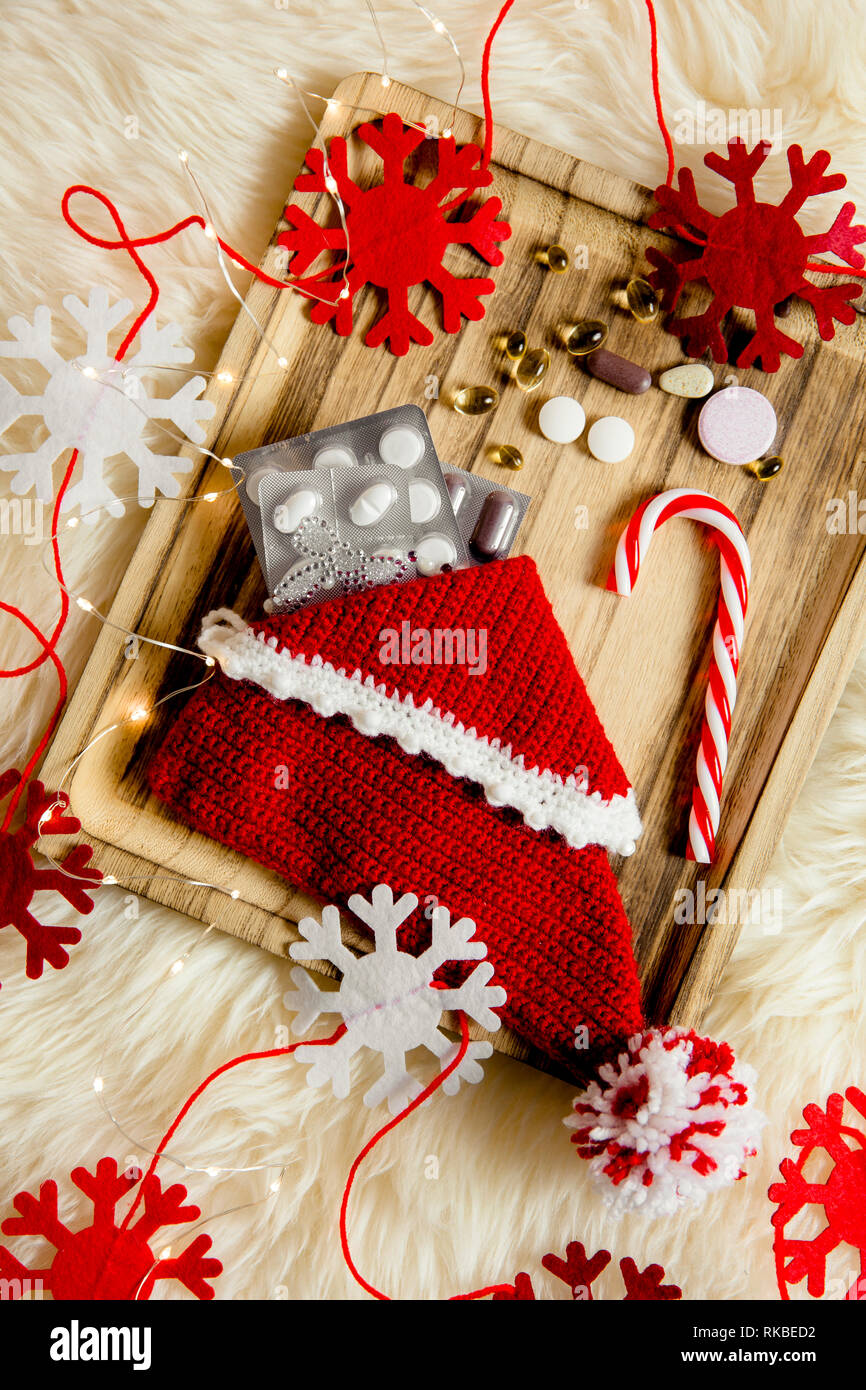 Vista dall'alto di pillole diverse vitamine come un regalo di Natale in pianelle calza su vintage vassoio in legno con fiocchi di neve in feltro come decorazione. Idea regalo conc Foto Stock