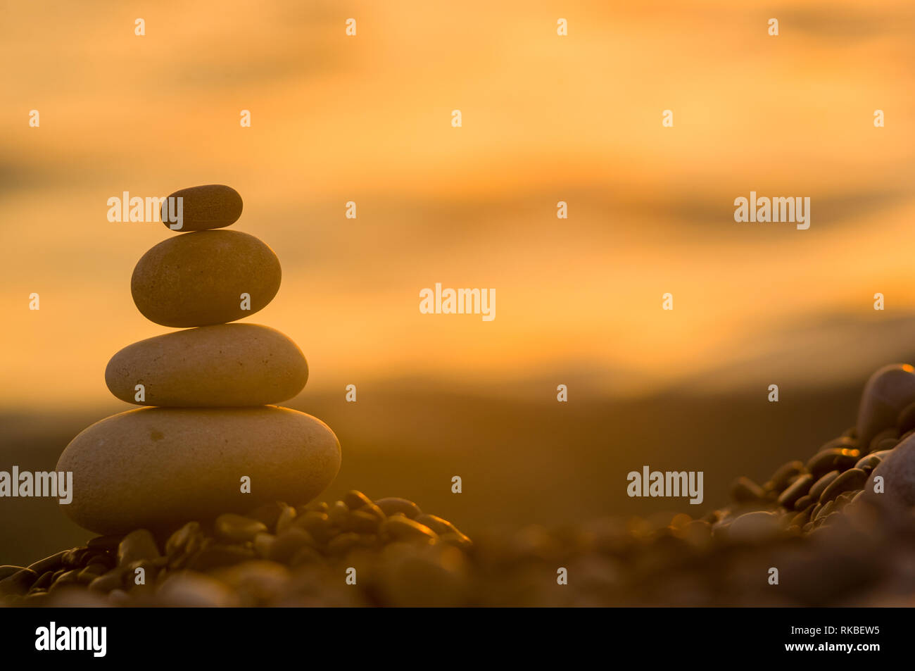 Piramide piegata Zen pietre ghiaia sul mare spiaggia al tramonto Foto Stock