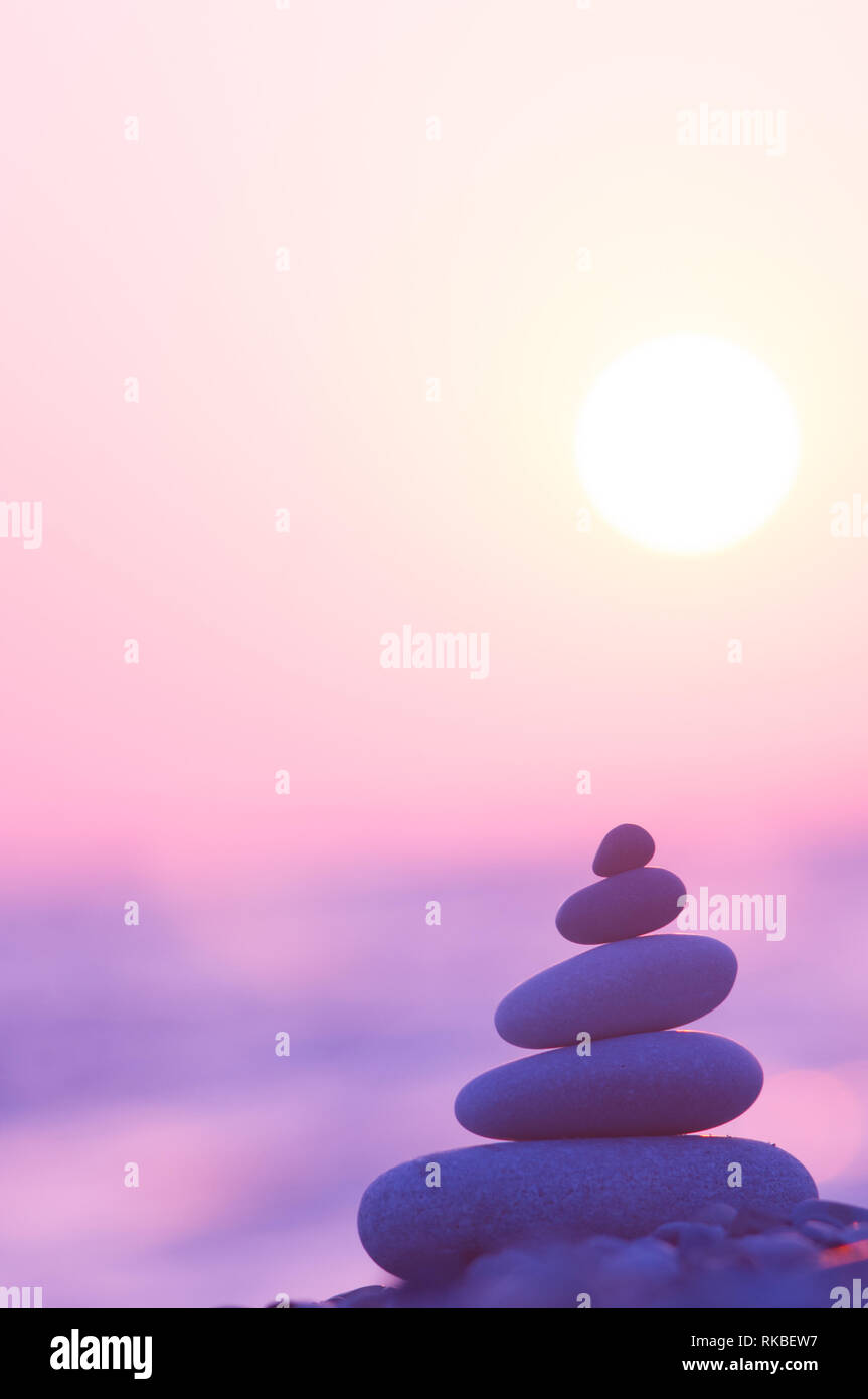 Piramide piegata Zen pietre ghiaia sul mare spiaggia al tramonto Foto Stock