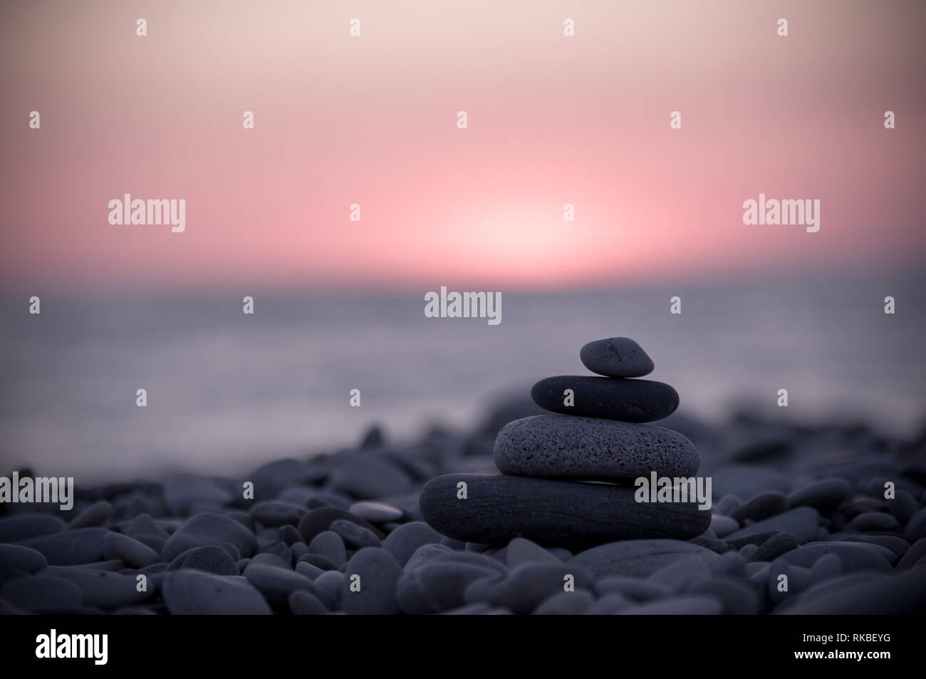 Piramide piegata Zen pietre ghiaia sul mare spiaggia al tramonto Foto Stock