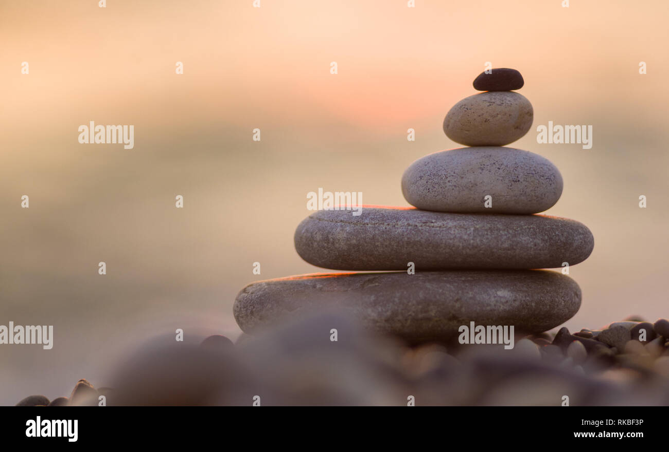 Piramide piegata Zen pietre ghiaia sul mare spiaggia al tramonto Foto Stock