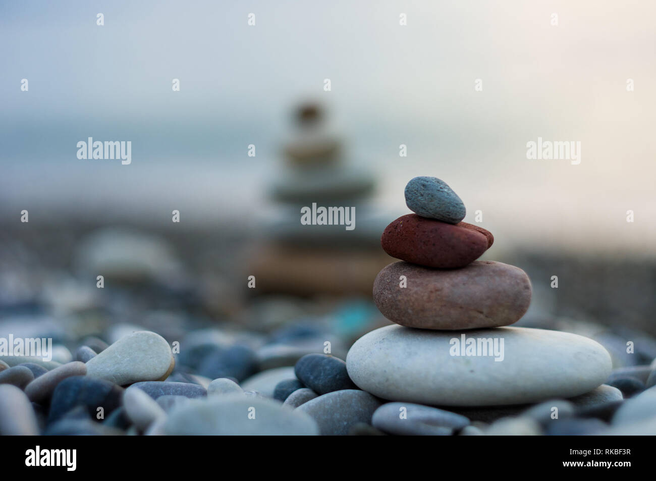 Piramide piegata Zen pietre ghiaia sul mare spiaggia al tramonto Foto Stock