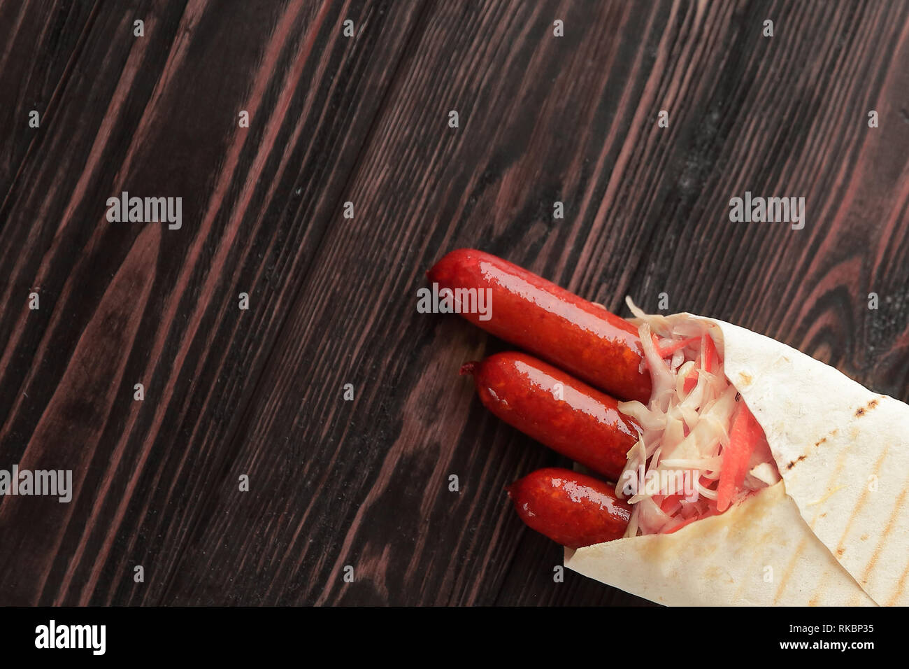Salsicce piccanti nel pane pita su sfondo di legno.foto con co Foto Stock