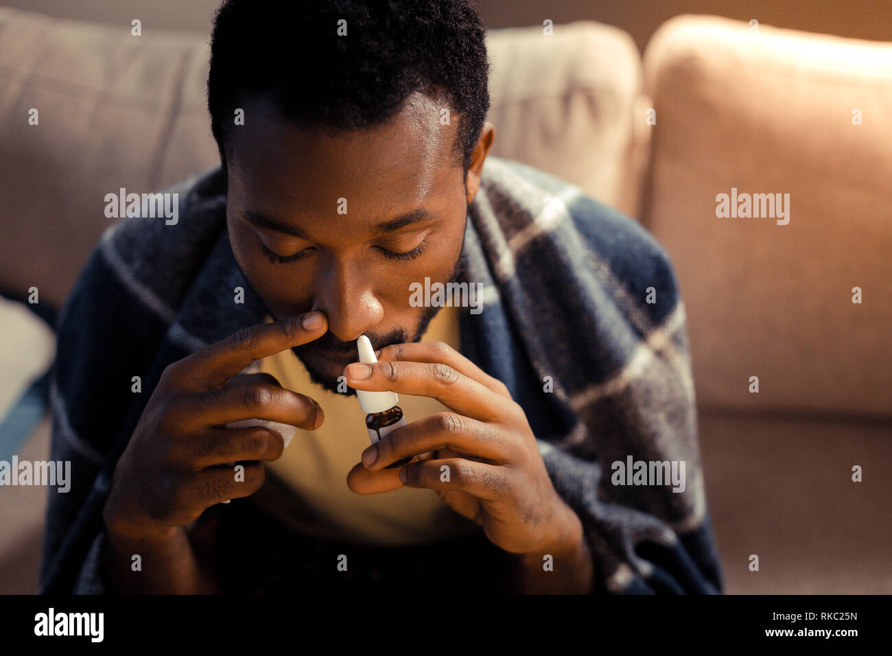 Afro-americano di uomo con spray nasale pur avendo acceso naso Foto Stock