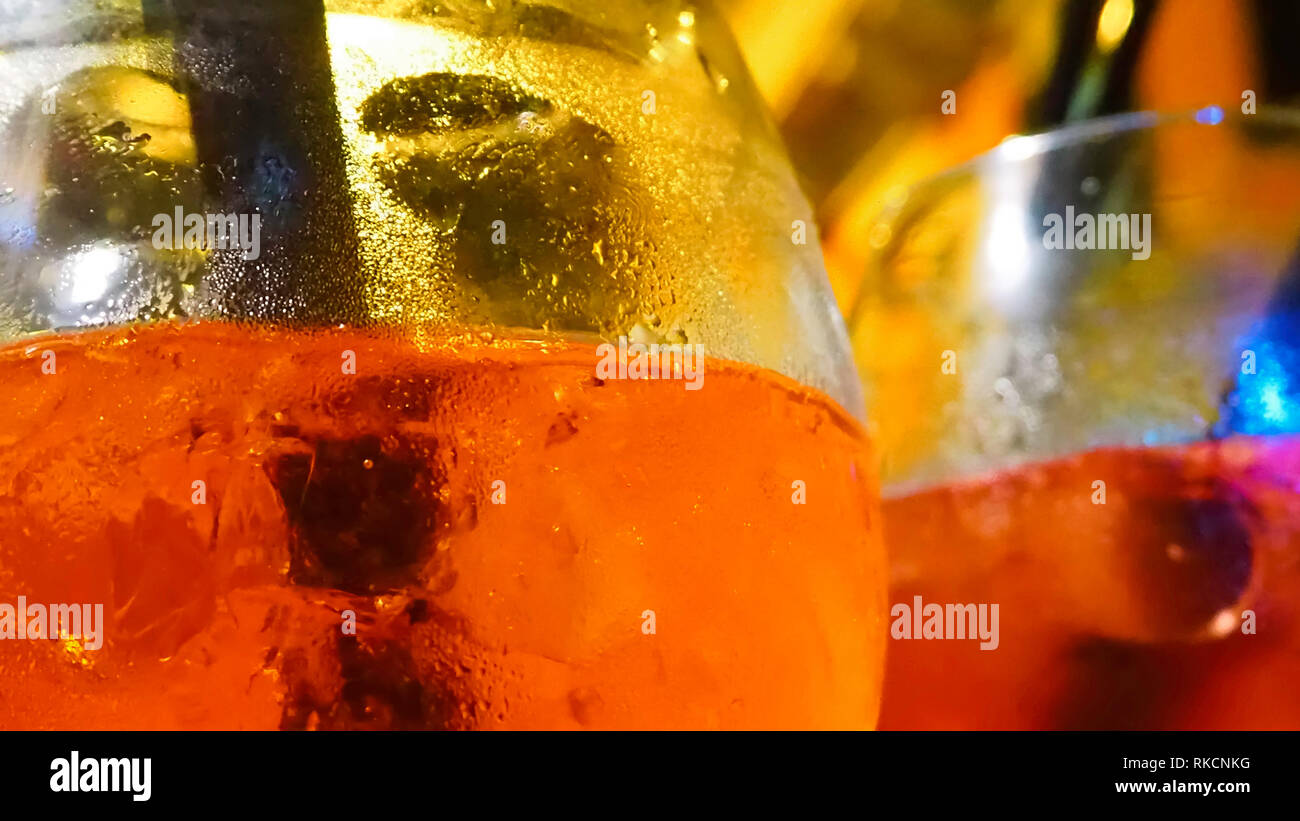 Aperitivo alcolico appena servito freddo e con ghiaccio. I colori degli occhiali sono di colore rosso e giallo e ci sono i tradizionali cannucce. Foto Stock