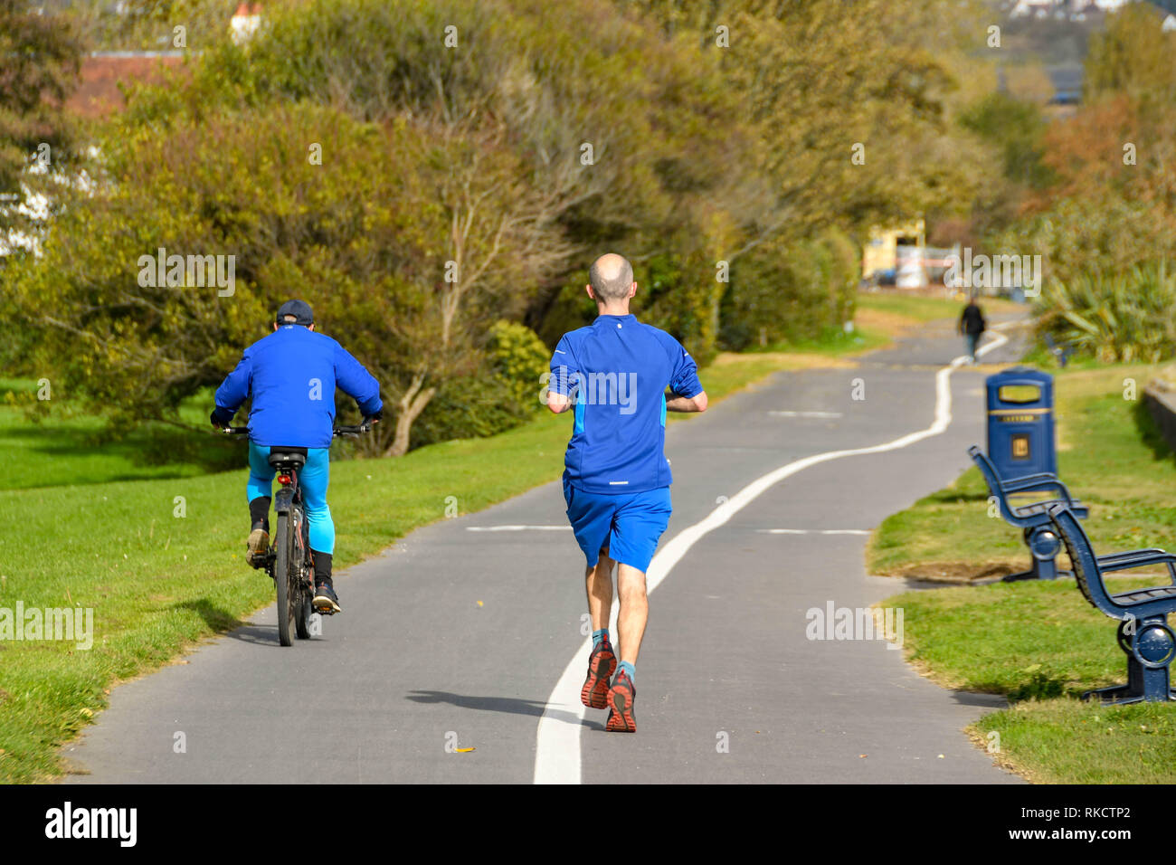SWANSEA, GALLES - Ottobre 2018: persona che corre lungo il percorso costiero da Mumbles a Swansea e una persona in bicicletta passato. Foto Stock