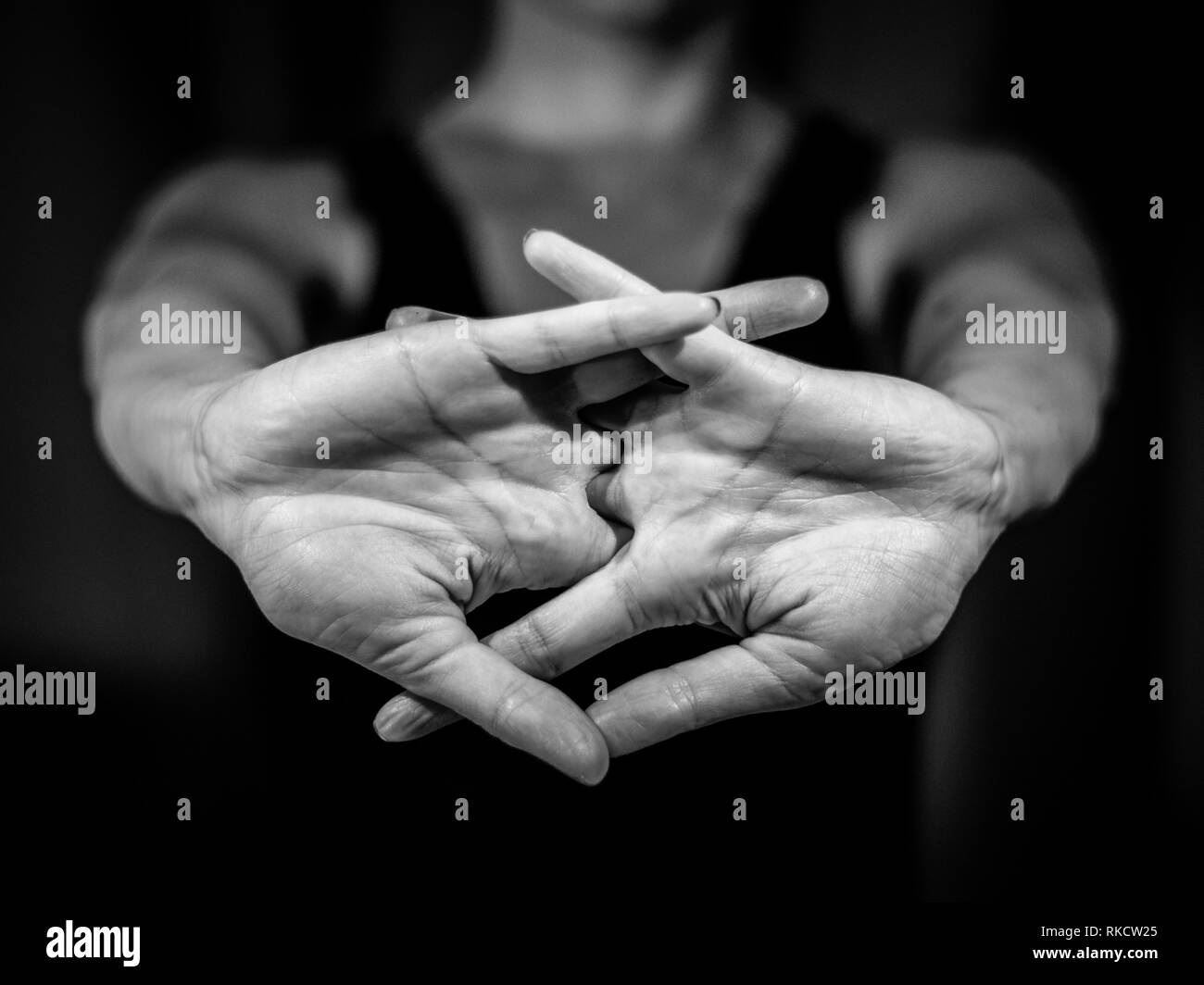 Foto in bianco e nero di giovane donna allungando il suo corpo con le sue mani nella parte anteriore. Knuckles, yoga , sport Foto Stock
