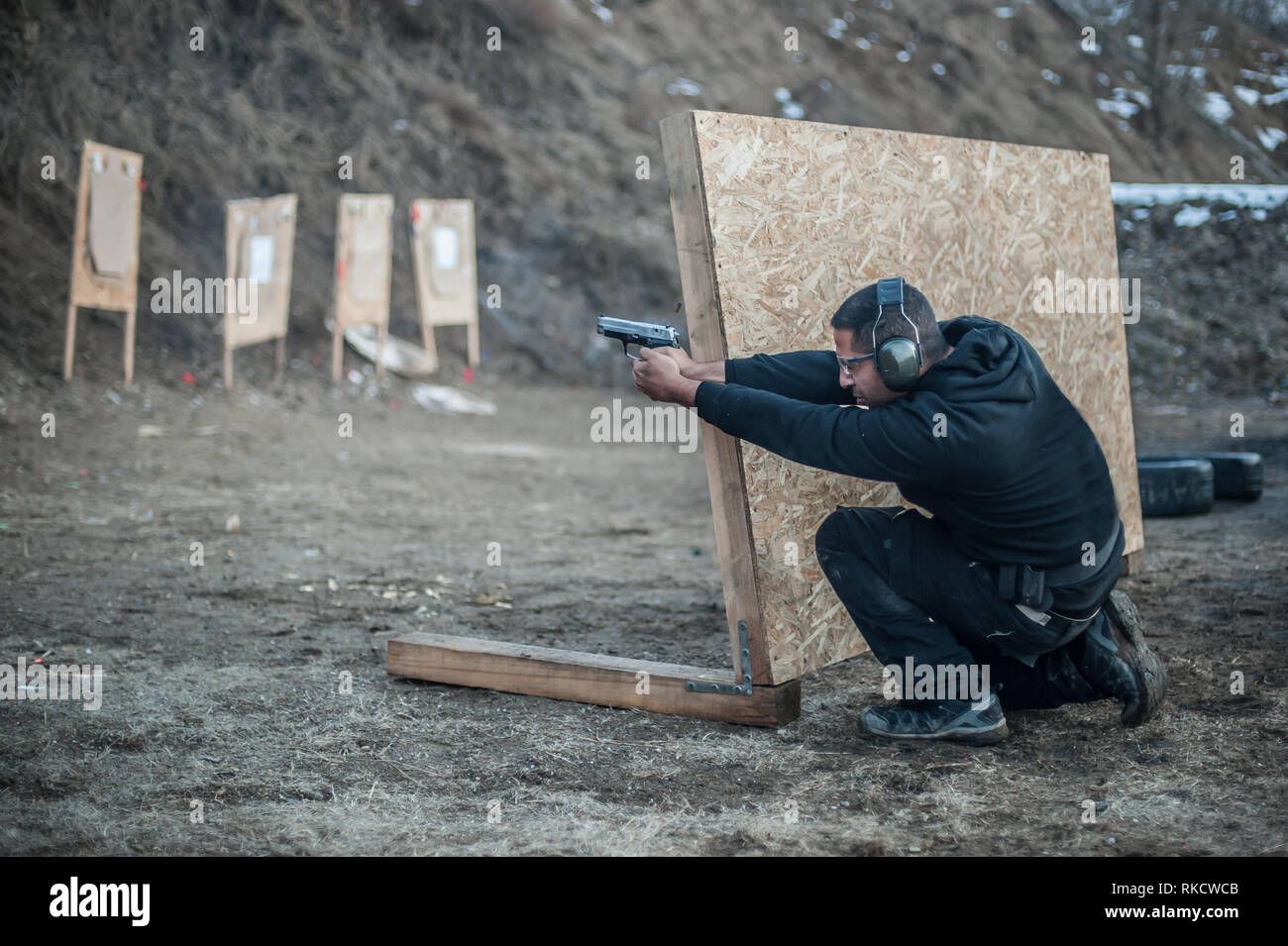 Pistola di combattimento addestramento al tiro da dietro e intorno al coperchio o barricade. Advanced combattimenti tattici corsi di tiro sul poligono di tiro Foto Stock