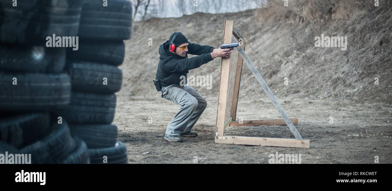 Pistola di combattimento addestramento al tiro da dietro e intorno al coperchio o barricade. Advanced combattimenti tattici corsi di tiro sul poligono di tiro Foto Stock